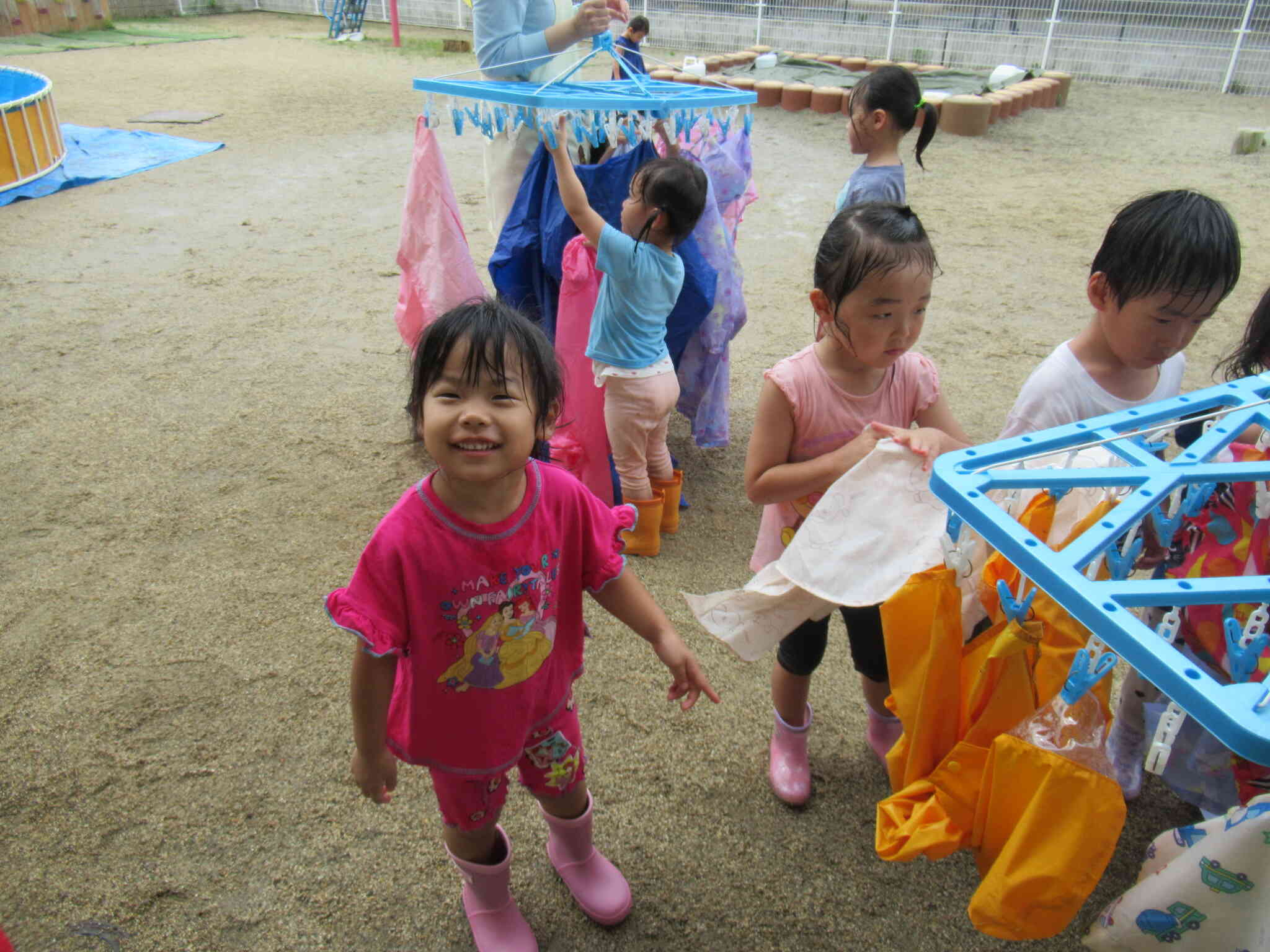 あ、雨が上がった！カッパはお洗濯しよう！ママが使ってる洗濯ばさみ、私もできるんだよ！ほら、みて！干せた！