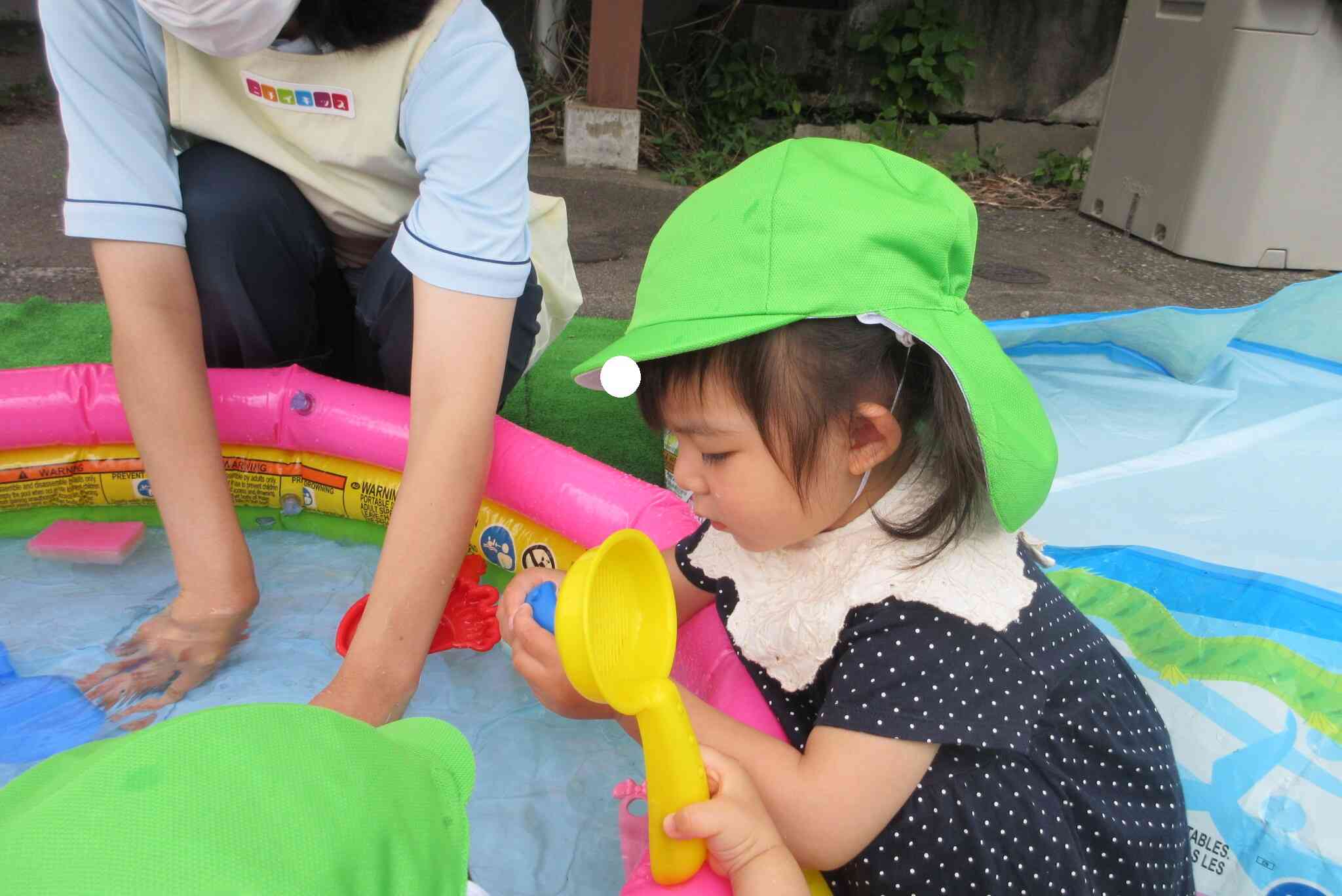 真剣に水鉄砲を見つめるお友達に「これも楽しいよ！」とおもちゃのおすそ分けをしているようです