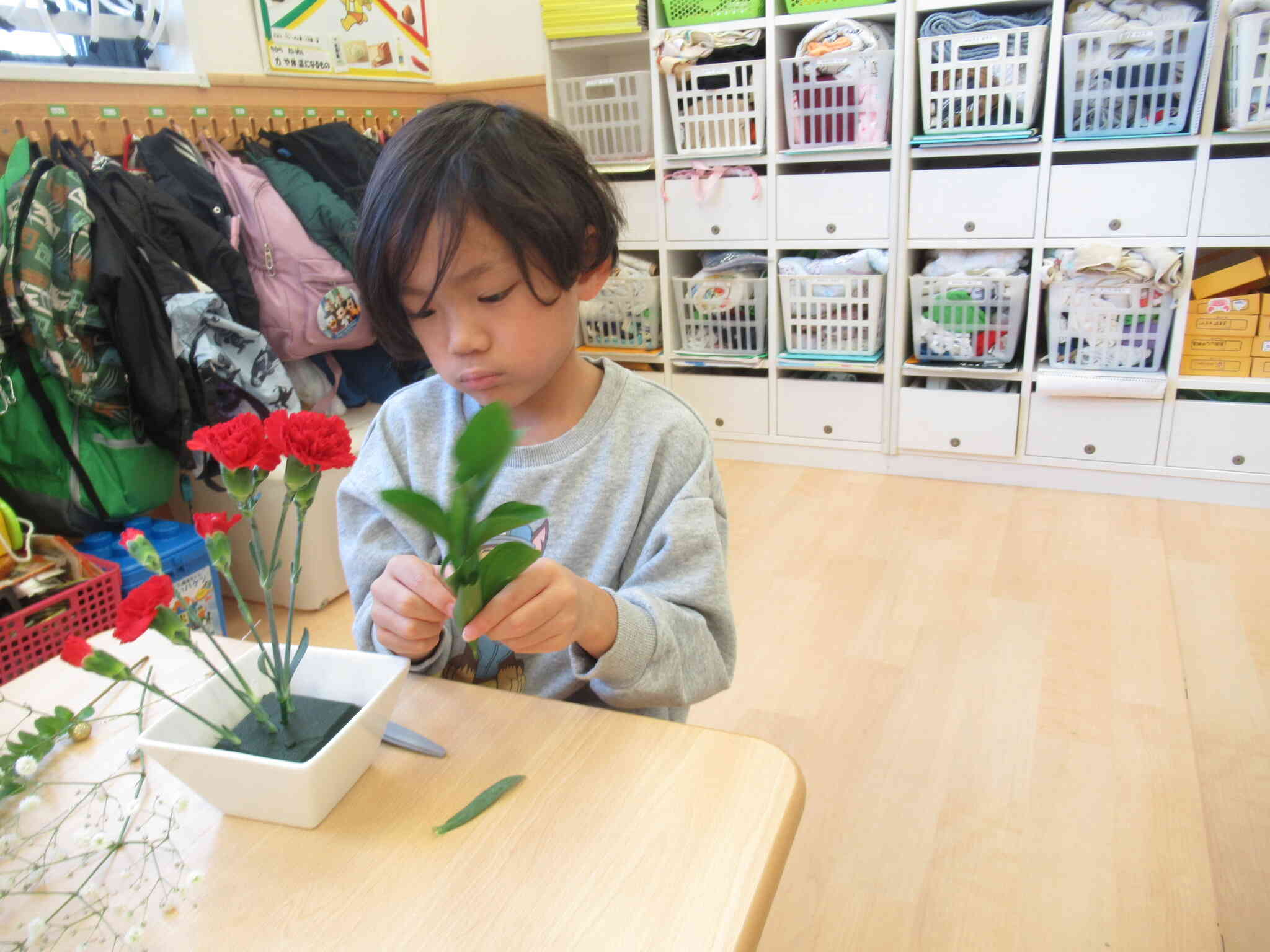 花器の真ん中にカーネーションを生けてからルスタスグリーンをカーネーションの後ろに生けました。