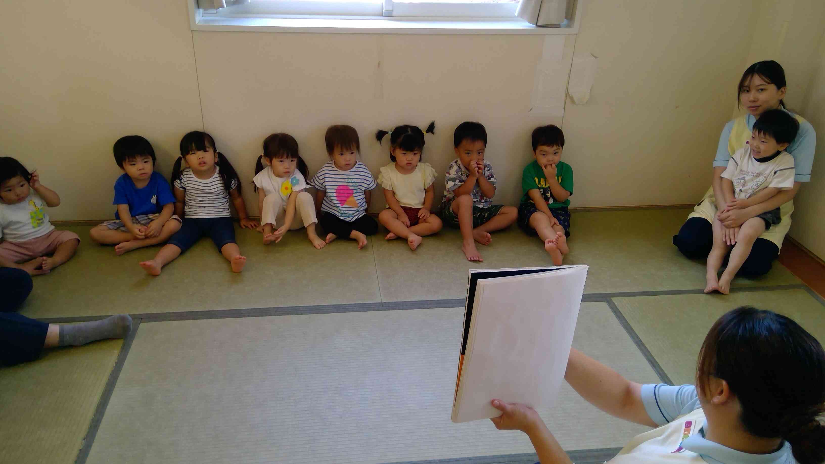 保育者のスケッチブックシアター、真剣な表情の子ども達。