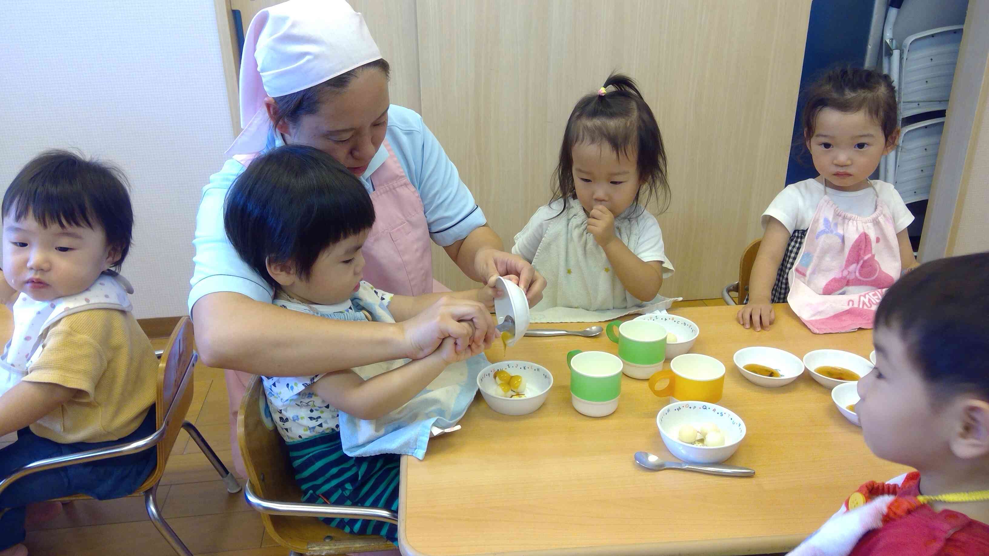 保育者と一緒に美味しそうなタレをかけるあひるぐみさん。