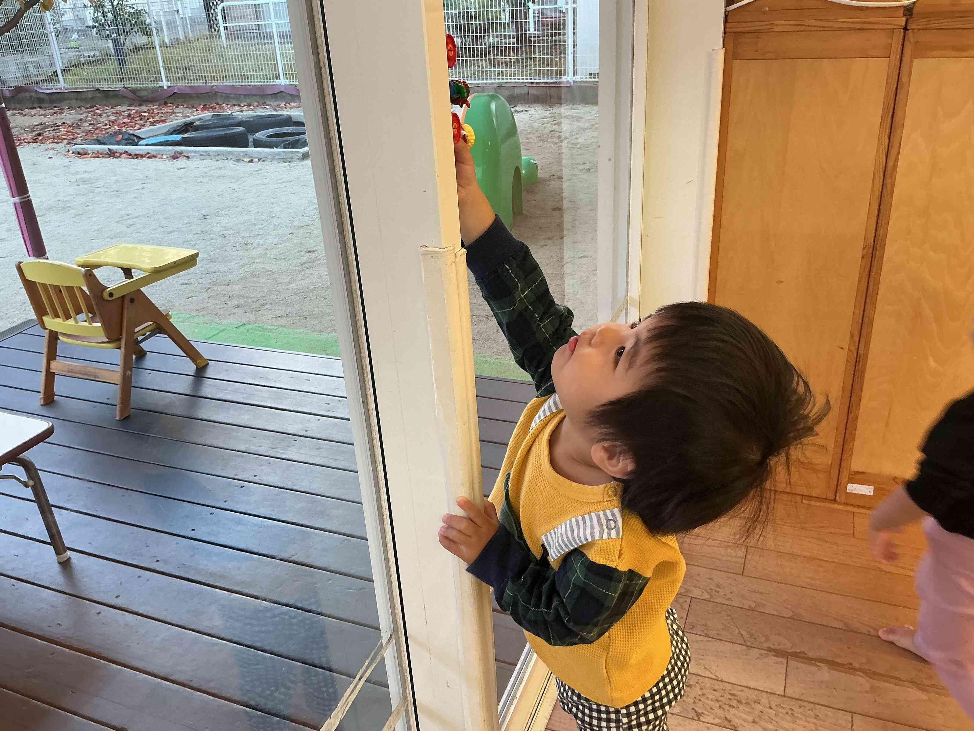 窓にくっついたおもちゃ、つま先立ちになって背伸びをして「よ~しつかまえた~」。