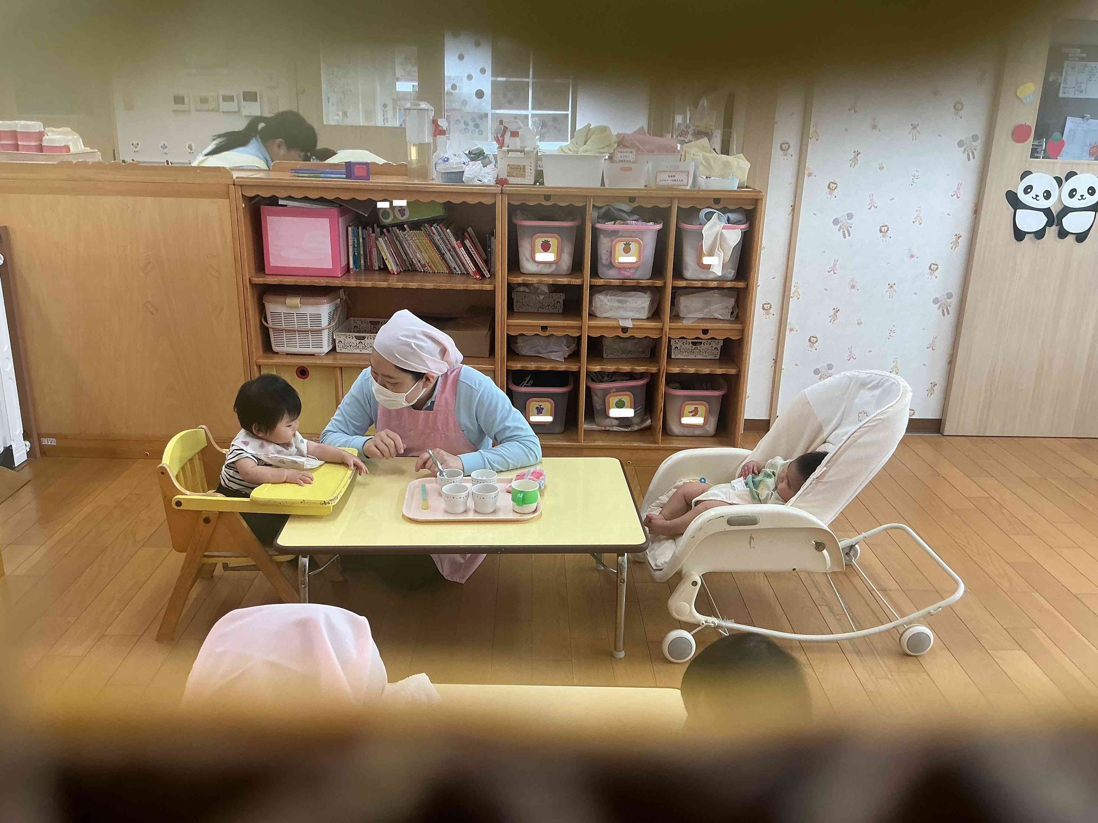 のぞき穴から見たひよこぐみ(0歳児)さんの給食の風景です。「いただきま~す」