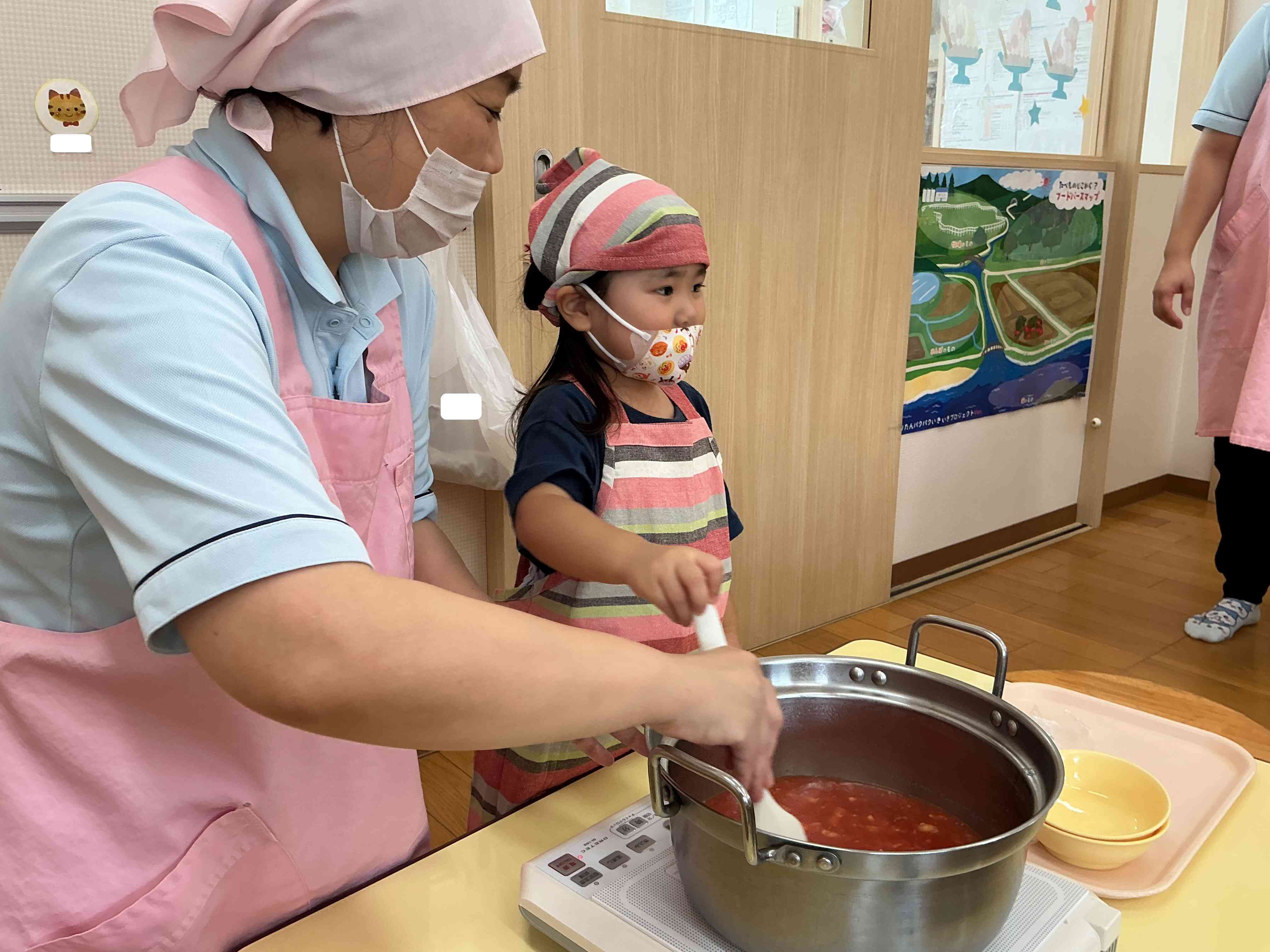 栄養士の先生と一緒に、お鍋のトマトをまぜまぜ~。
