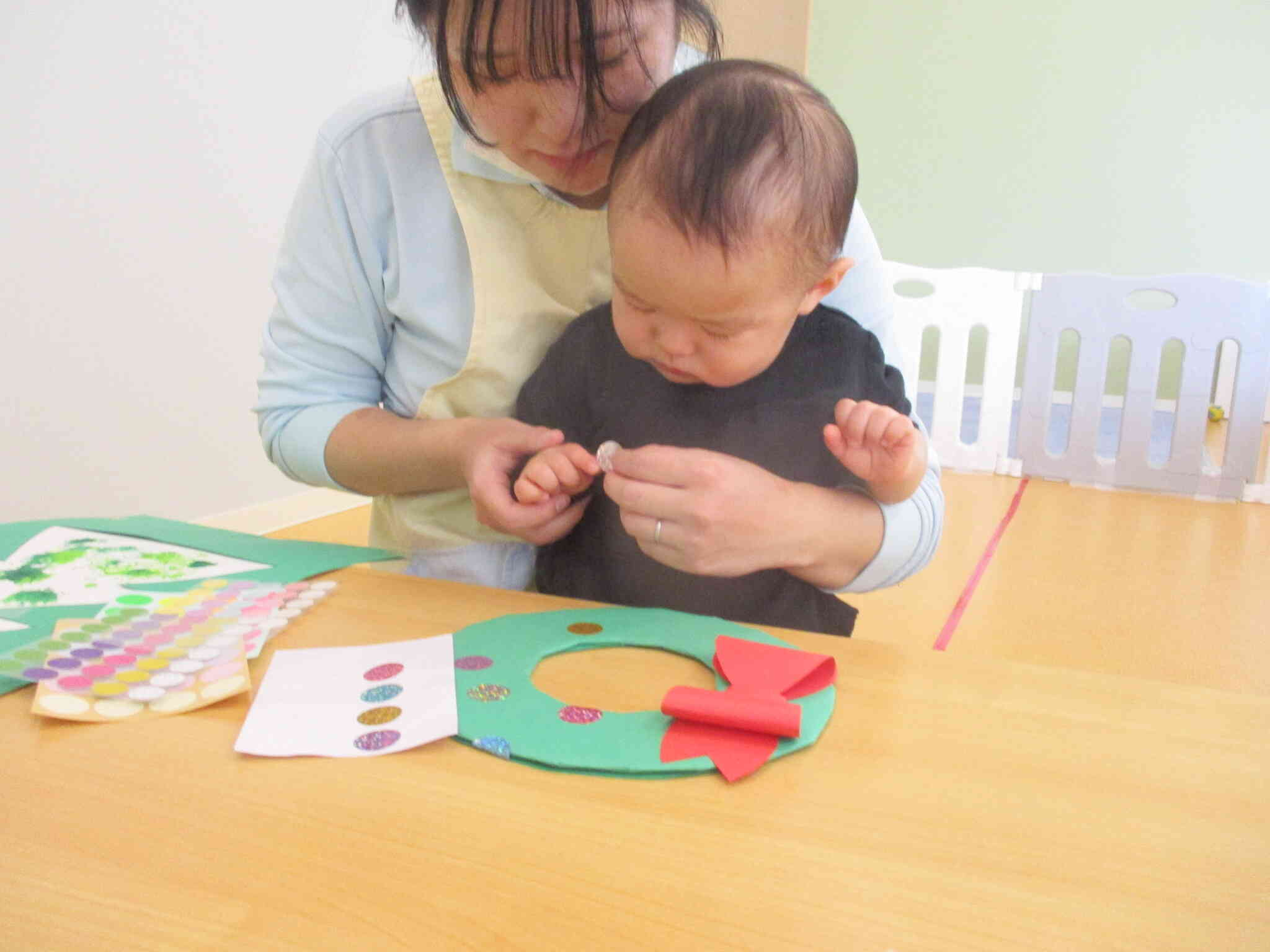 ひよこ組さん（０歳児クラス）はリースにシールを自分たちで貼って飾りつけしました！