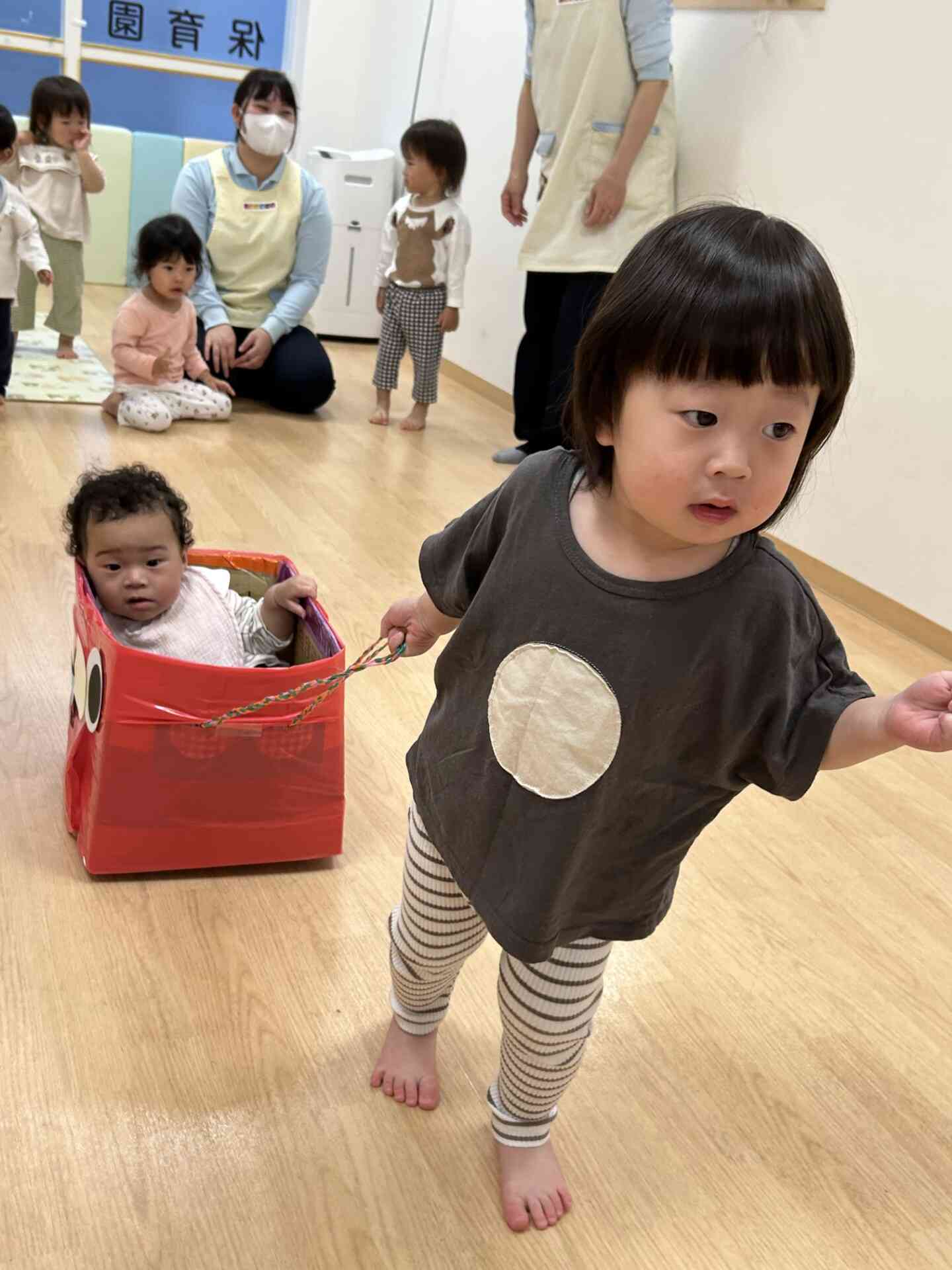 ２歳児うさぎ組さんは０歳児ひよこ組さんを乗せて「よいしょよいしょ」