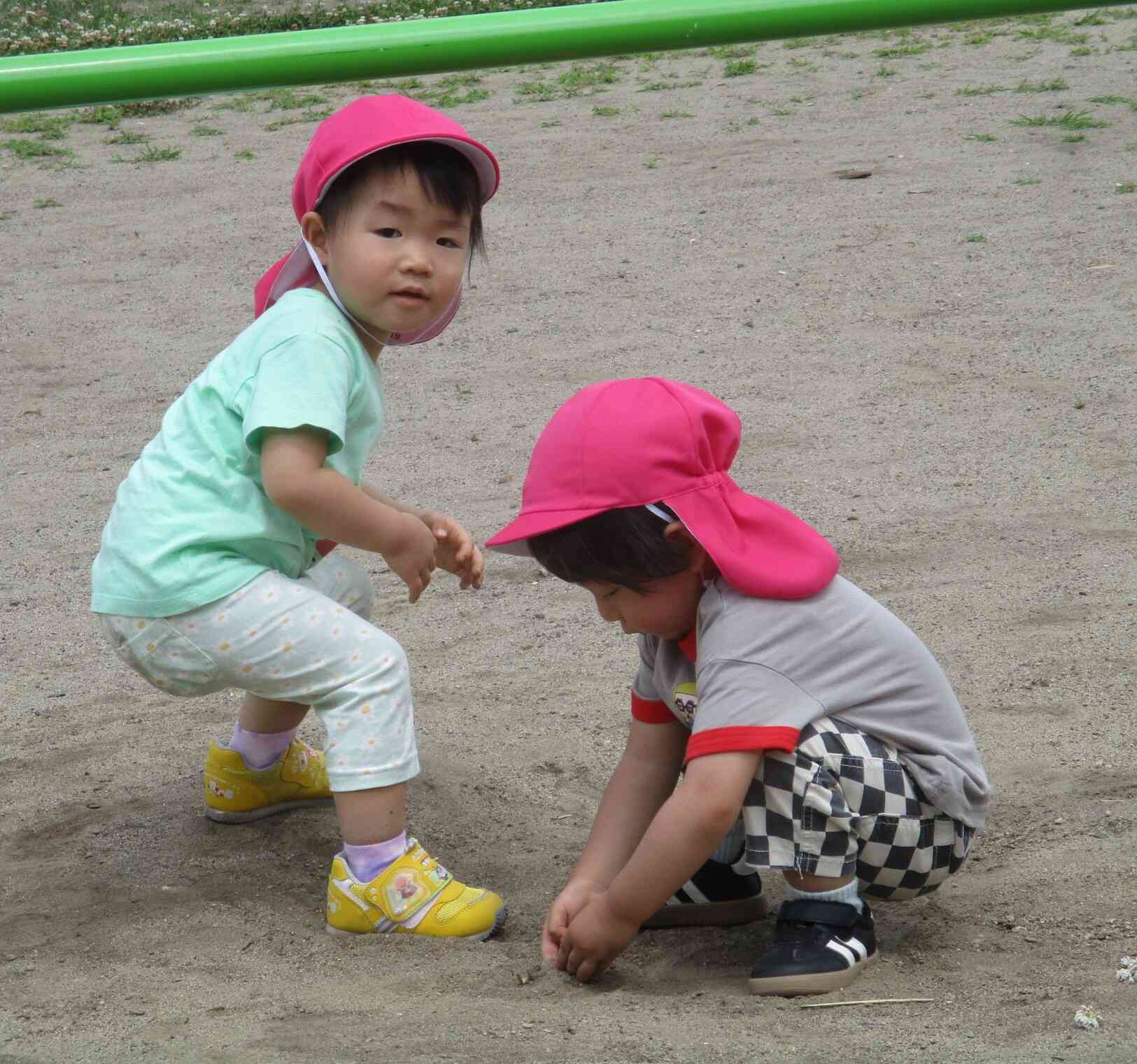 友だちとお絵描きしている所を撮られて恥ずかしそうなあひる組（１歳児）の女の子。