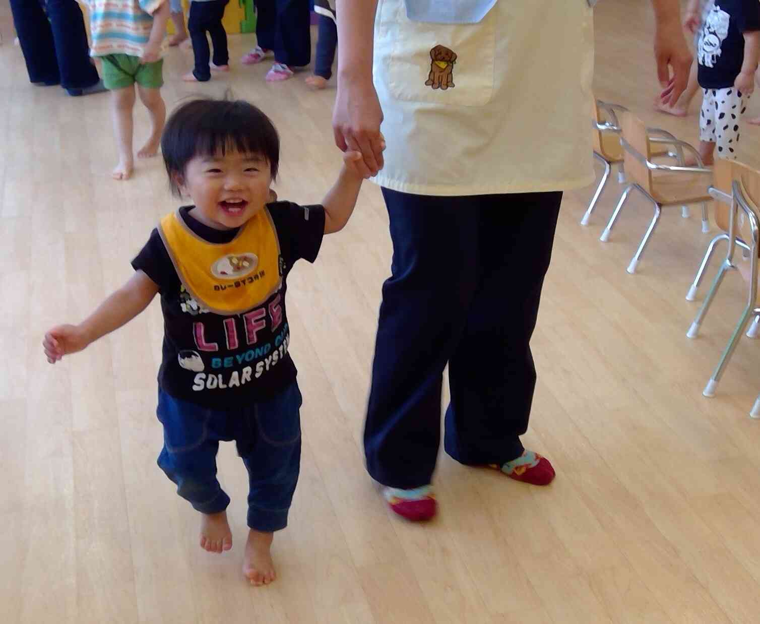 先生と手を繋いで嬉しそうなあひる組（1歳児）の男の子