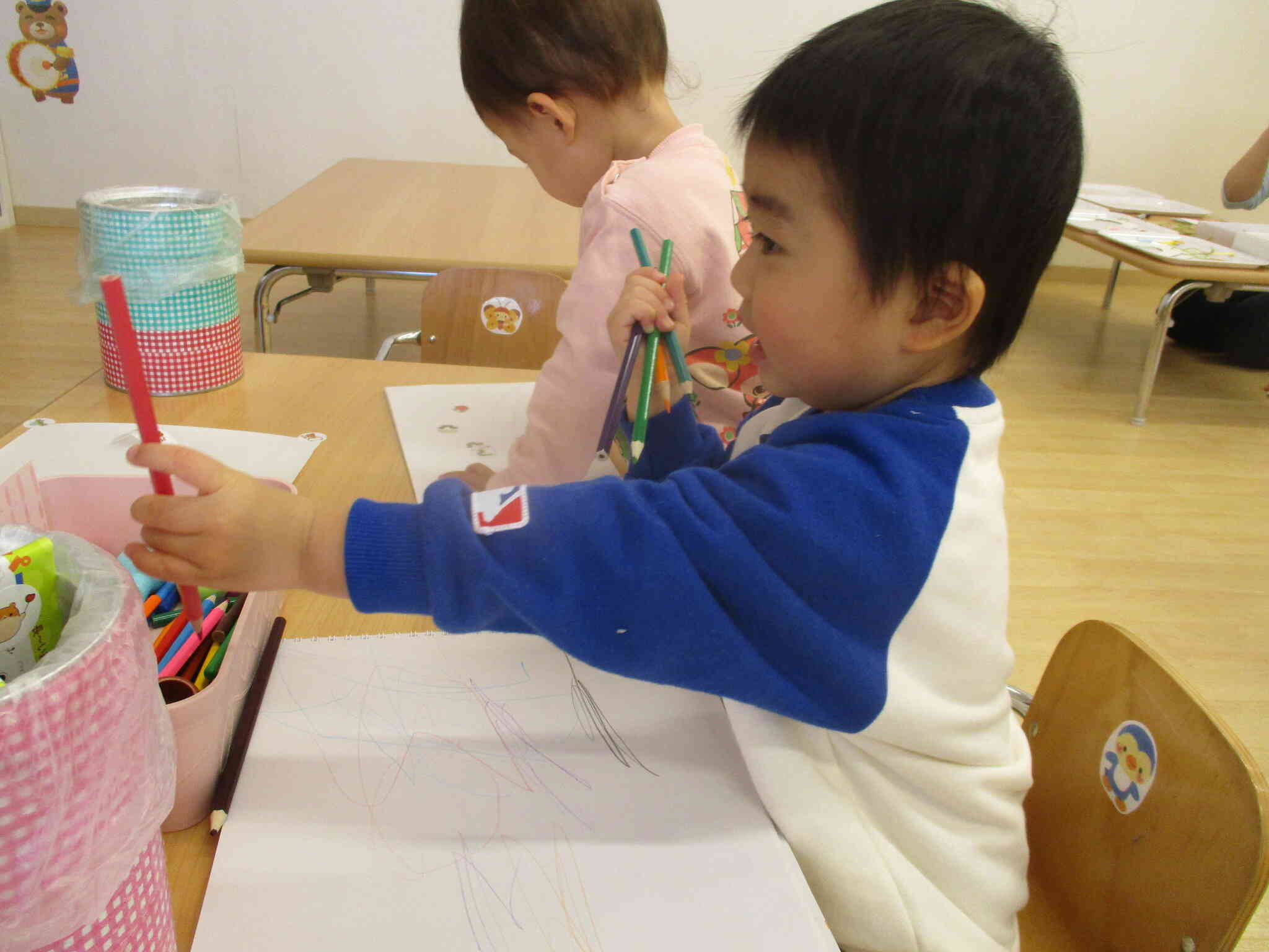 「貸してあげる～」と、向かいのお友だちに色鉛筆を渡そうとする優しい男の子です。