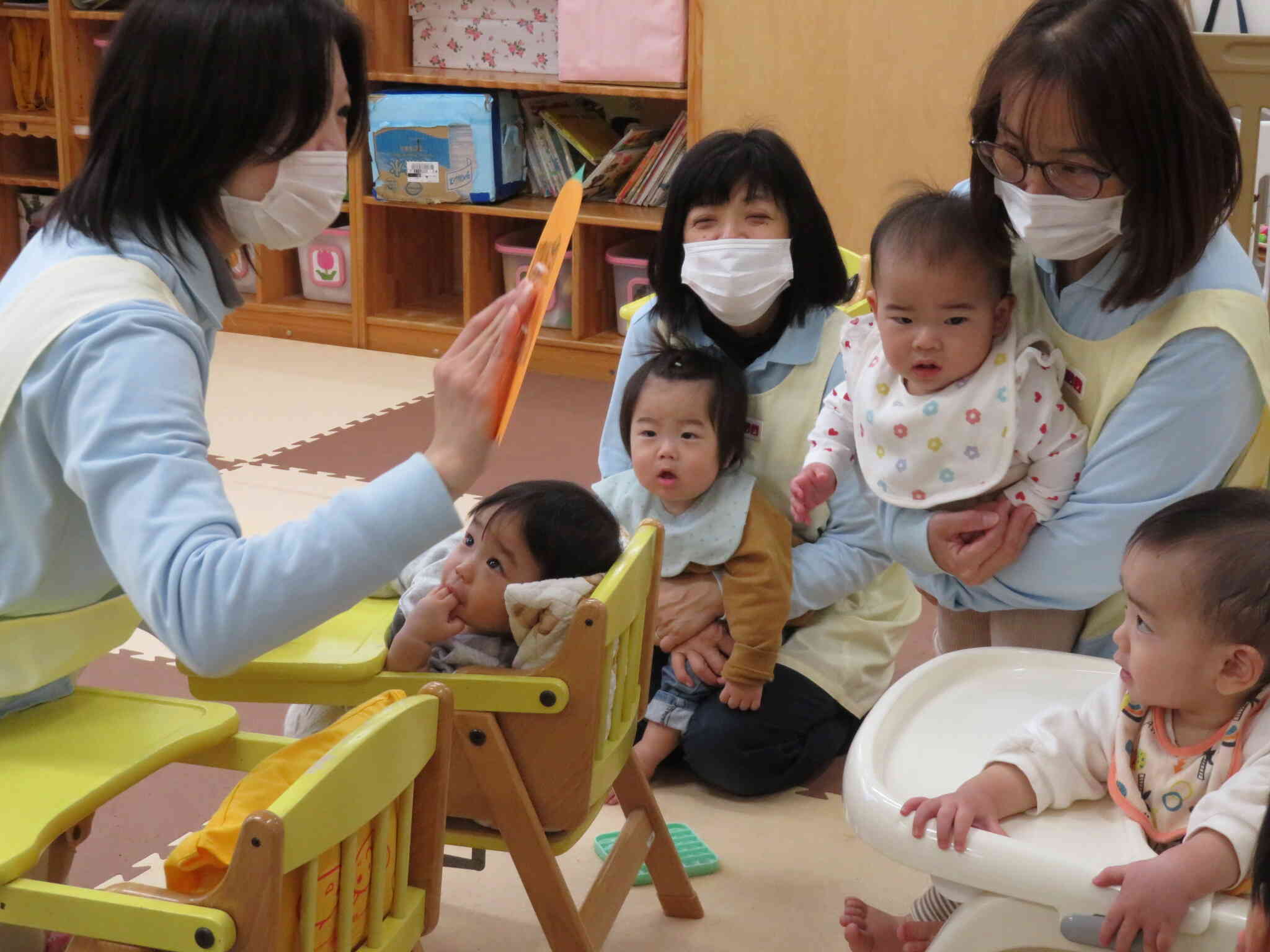 0歳児クラスの子ども達。　みんなで「くいしんぼおばけ」を見ています。