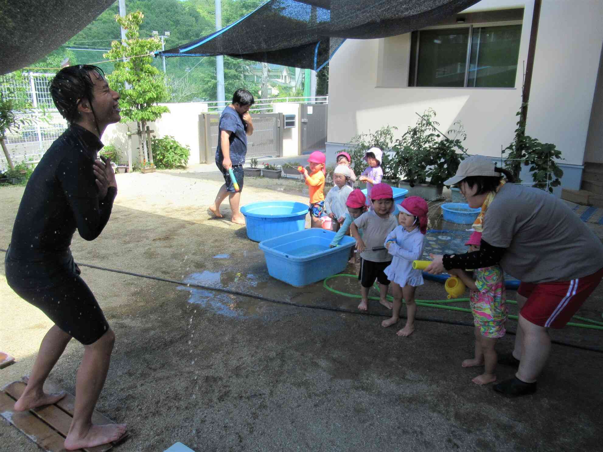 プールの隣で水遊びをしていたうさぎ組さん♪　体操教室の先生に、水鉄砲で元気いっぱいにごあいさつ！