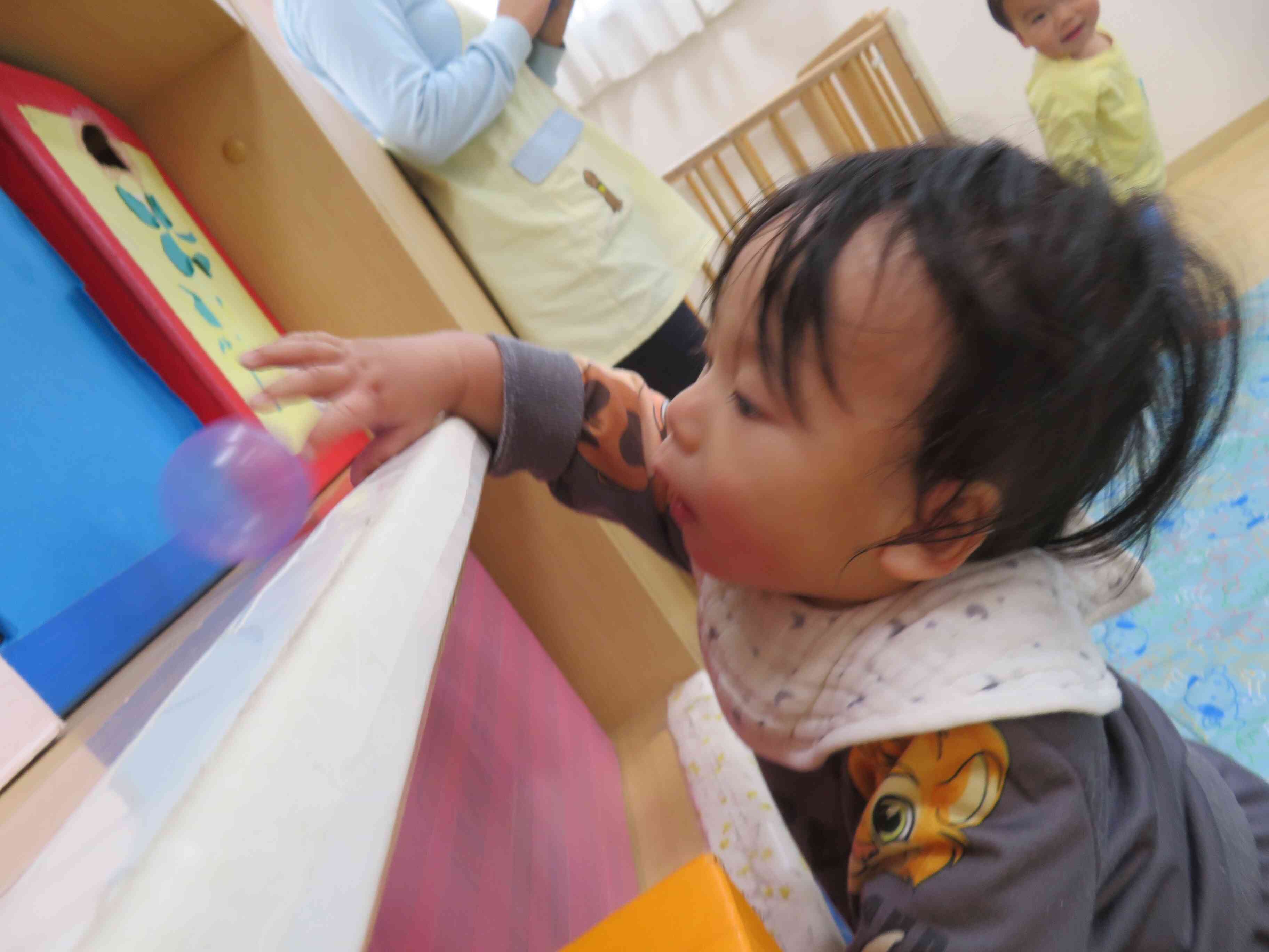 つかまり立ちをして、一生懸命手を伸ばしてボールをとろうとしています。でもコロコロ転がってなかなかとれなかったね。