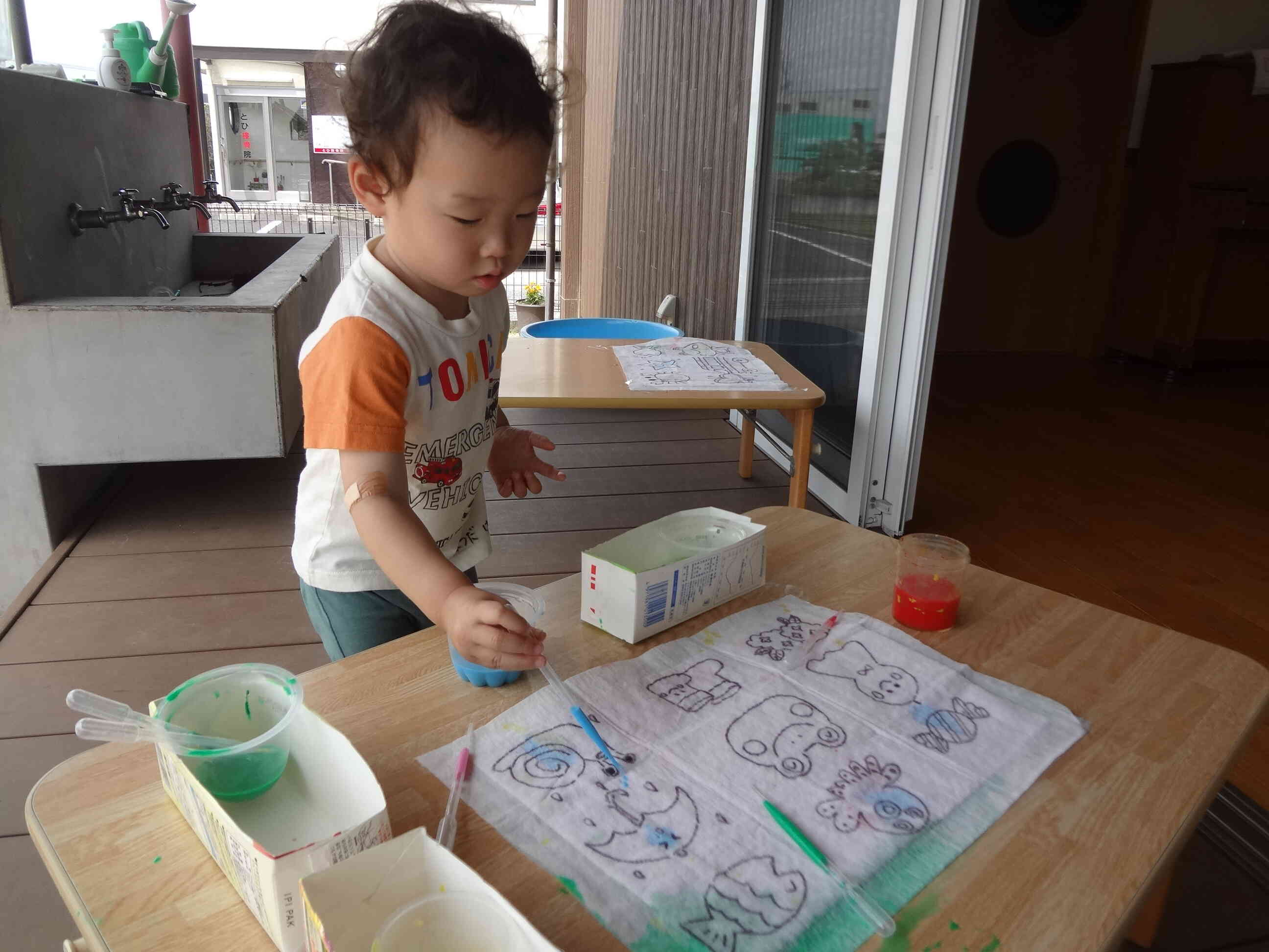 自分たちで作った色水を持ってテラスにでました。スポイトをつかって給水紙にポタポタと色をつけていきます。