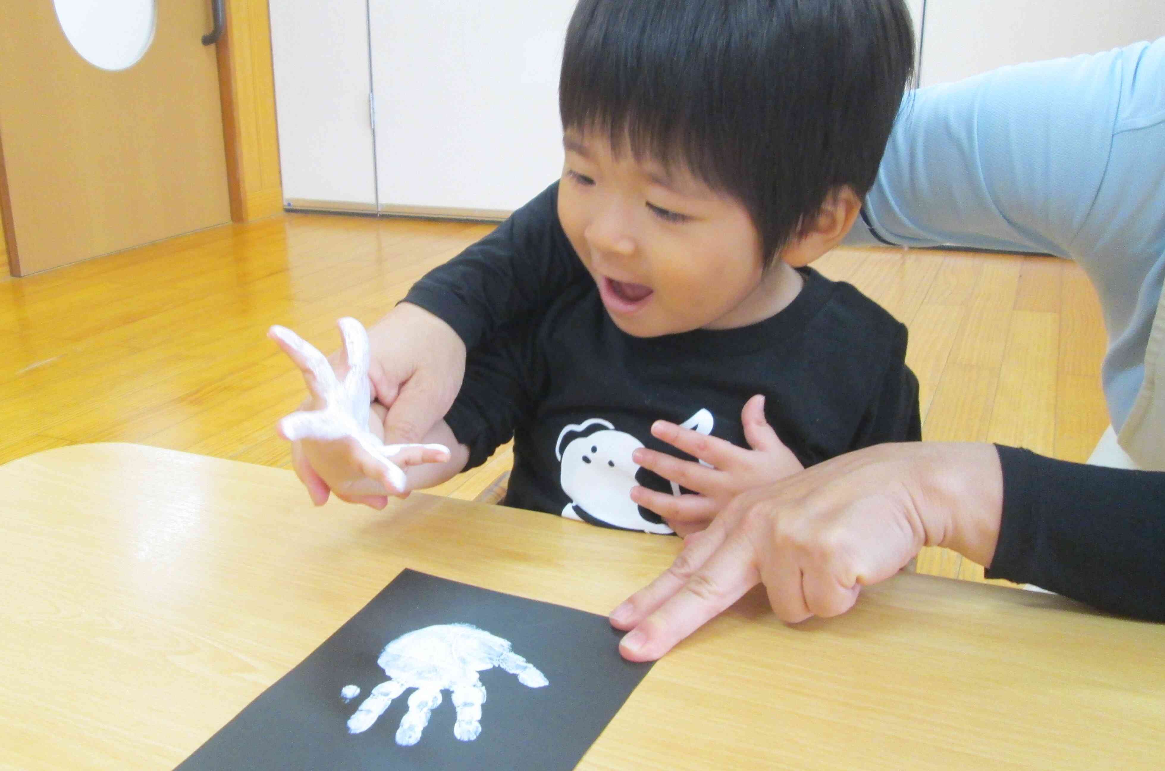 画用紙につけた手形と見比べていますね。