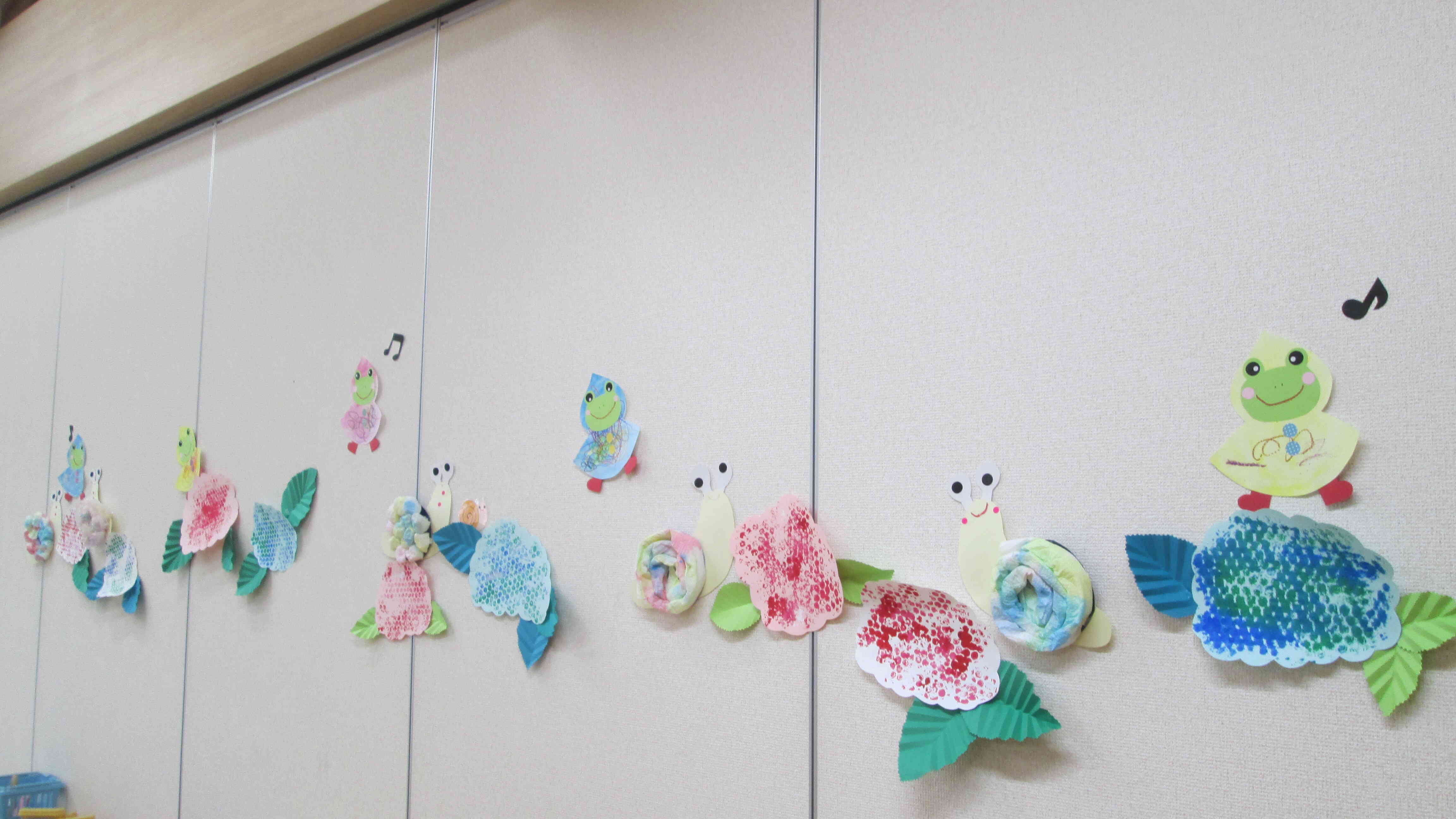 絵の具を塗ってはじき絵になったカエルができました！先日のあじさい、かたつむりと並んで賑やかな壁面になりました！
