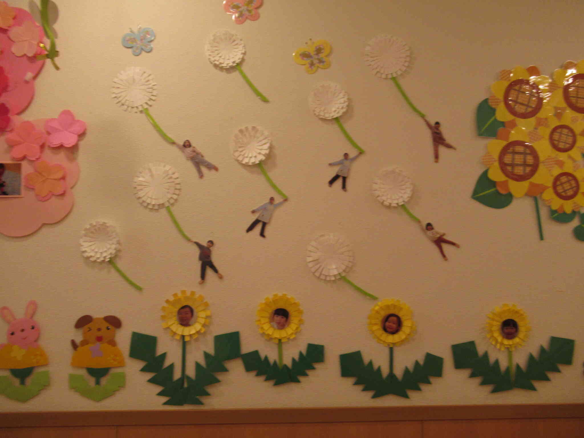 たんぽぽのわたげと一緒に卒園児さんと先生が飛んでいます。