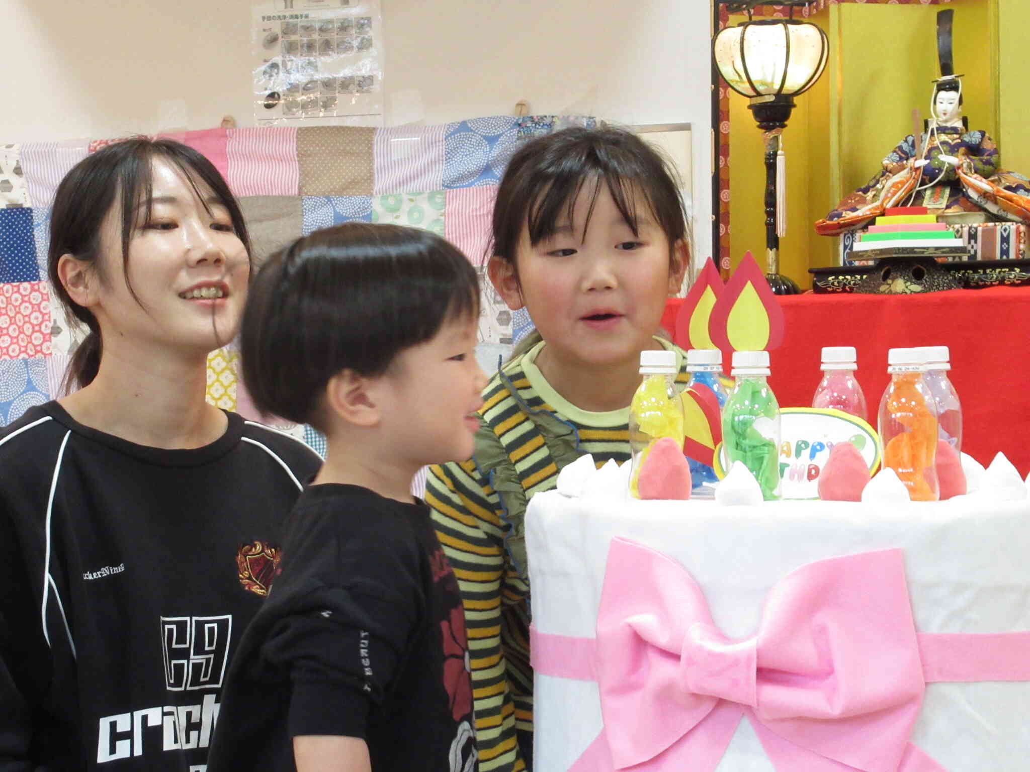 お誕生日会でケーキのローソクを消しました。優しいお姉ちゃんが手伝ってくれました。 新さくら組(3歳児)