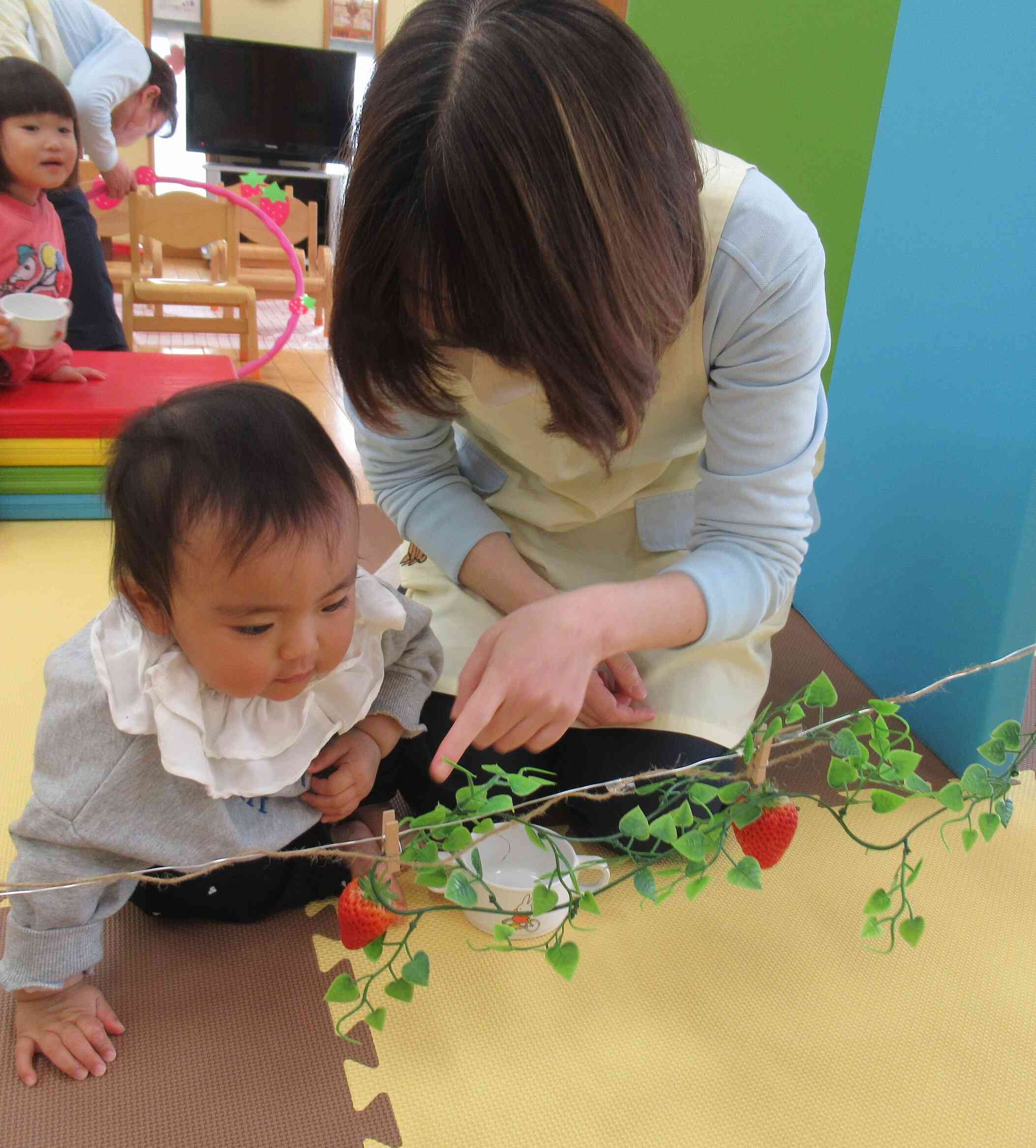 「わたしも、とりたいな」０歳児さんも、いちごに興味津々です。