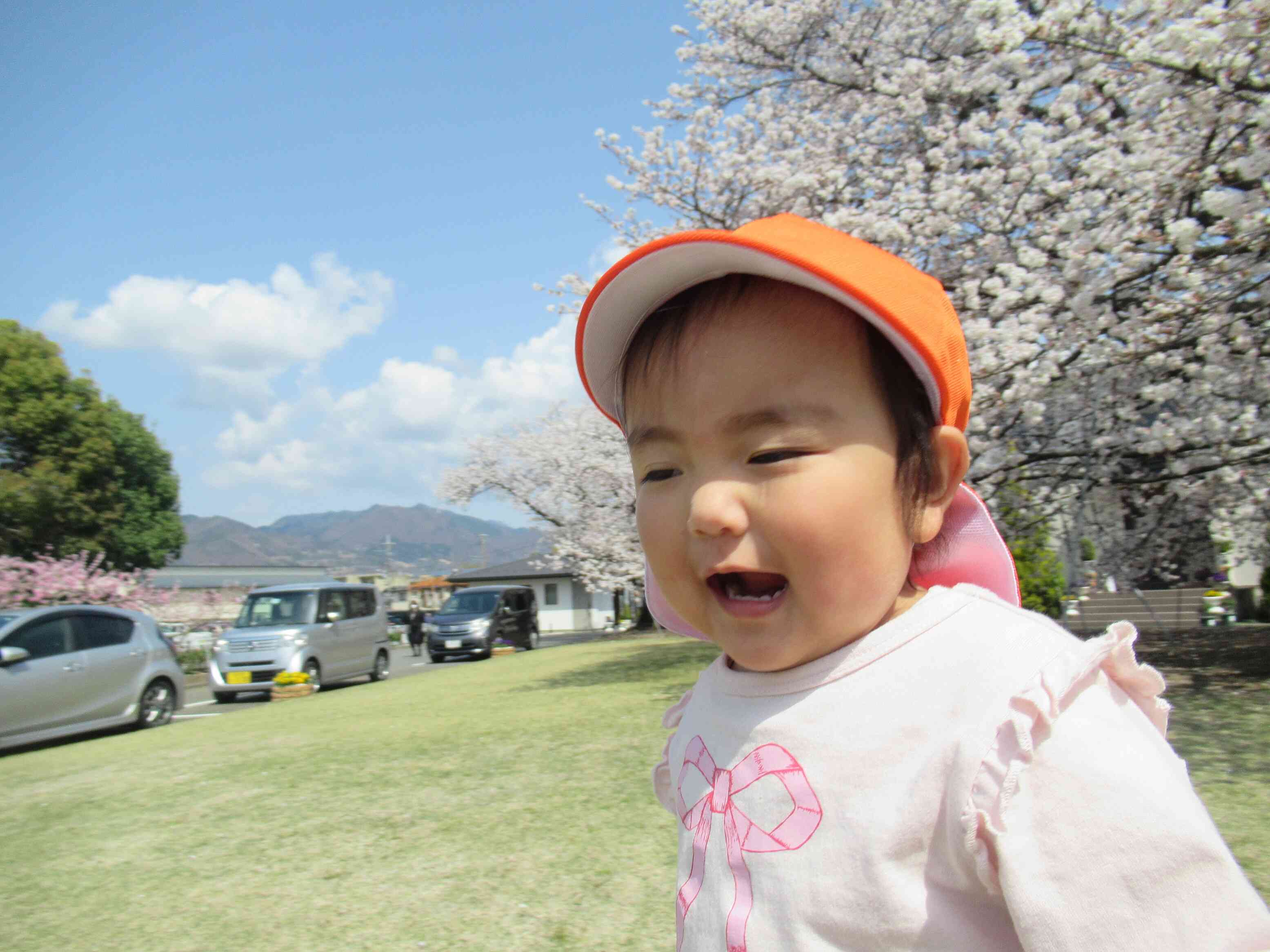 芝生の上に、何やら宝物？を見つけて、思わず笑顔の１歳児さん。