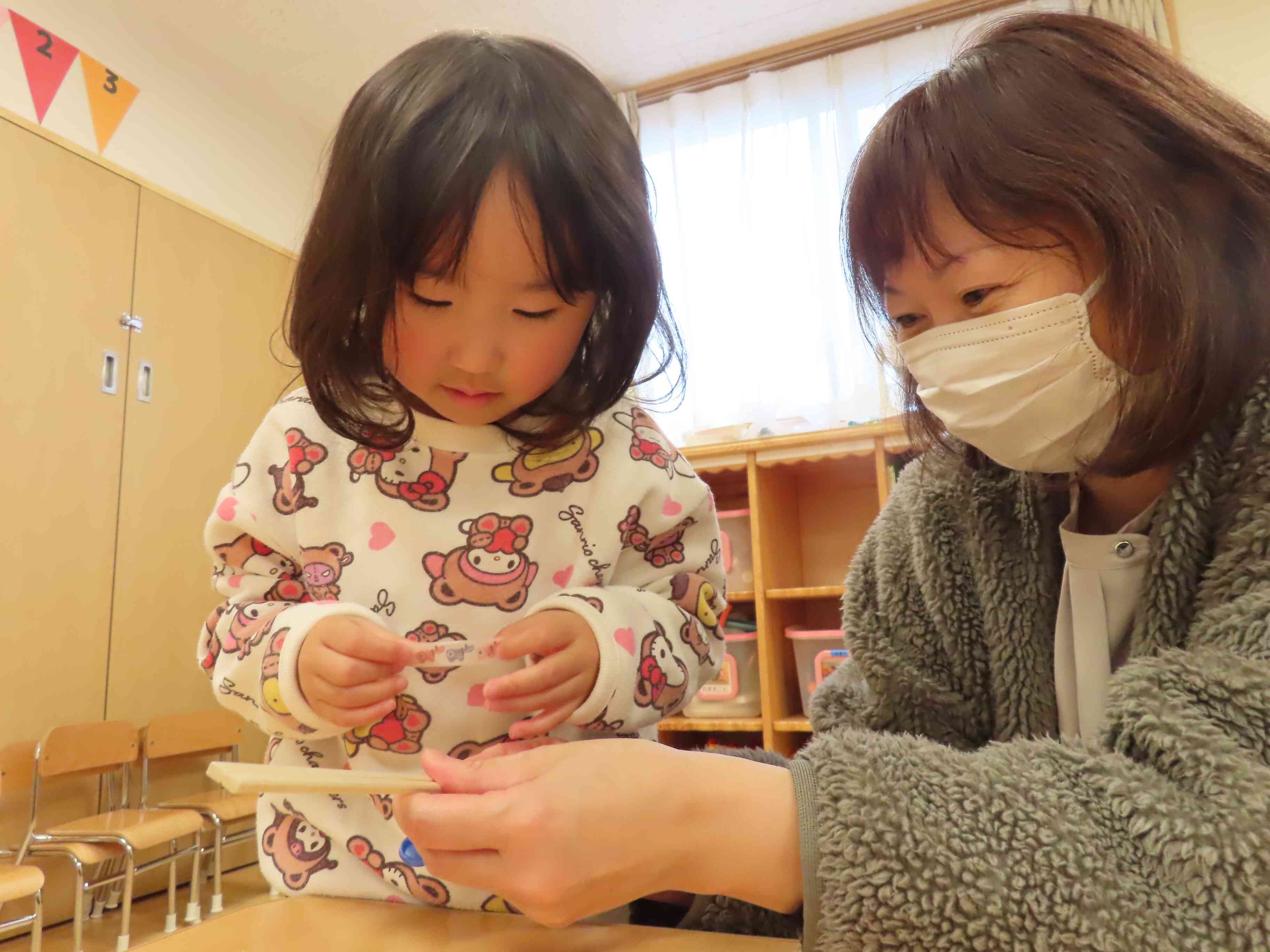 ママ押さえててね。私がそっとテープを貼るね。