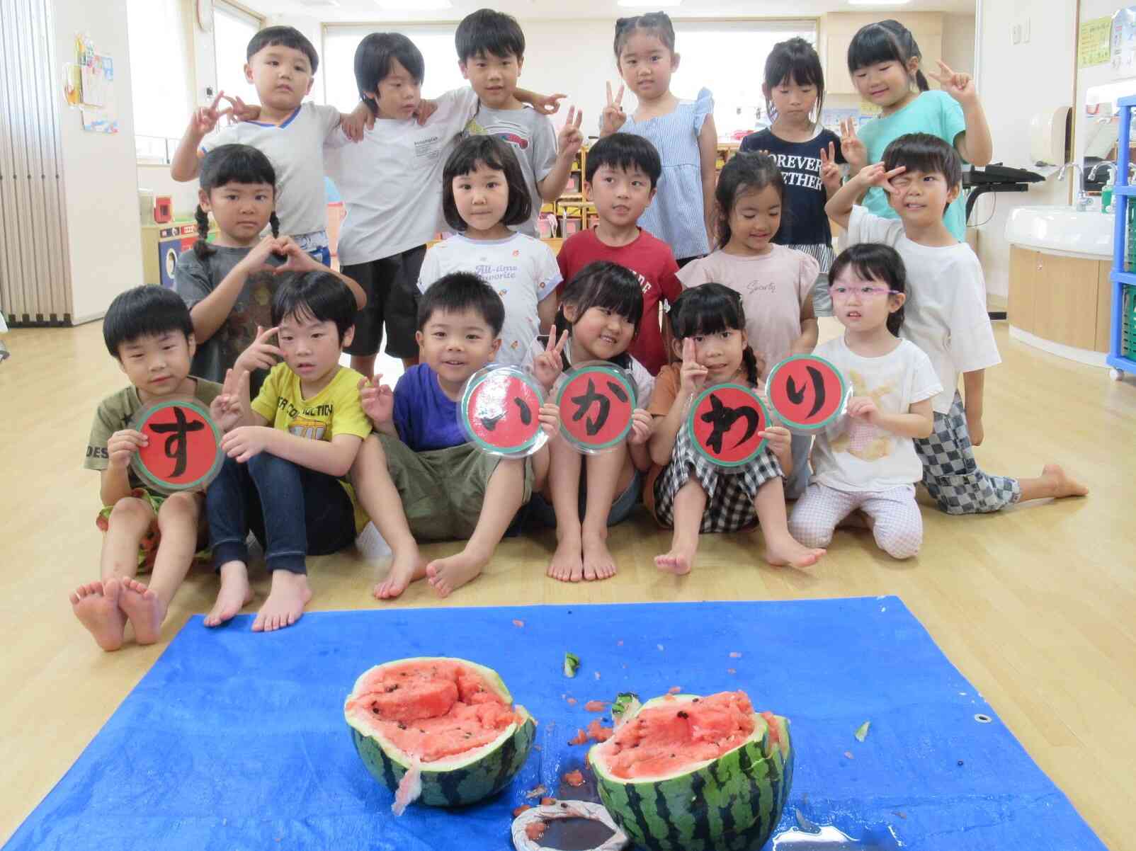 割れたすいかの前で記念写真