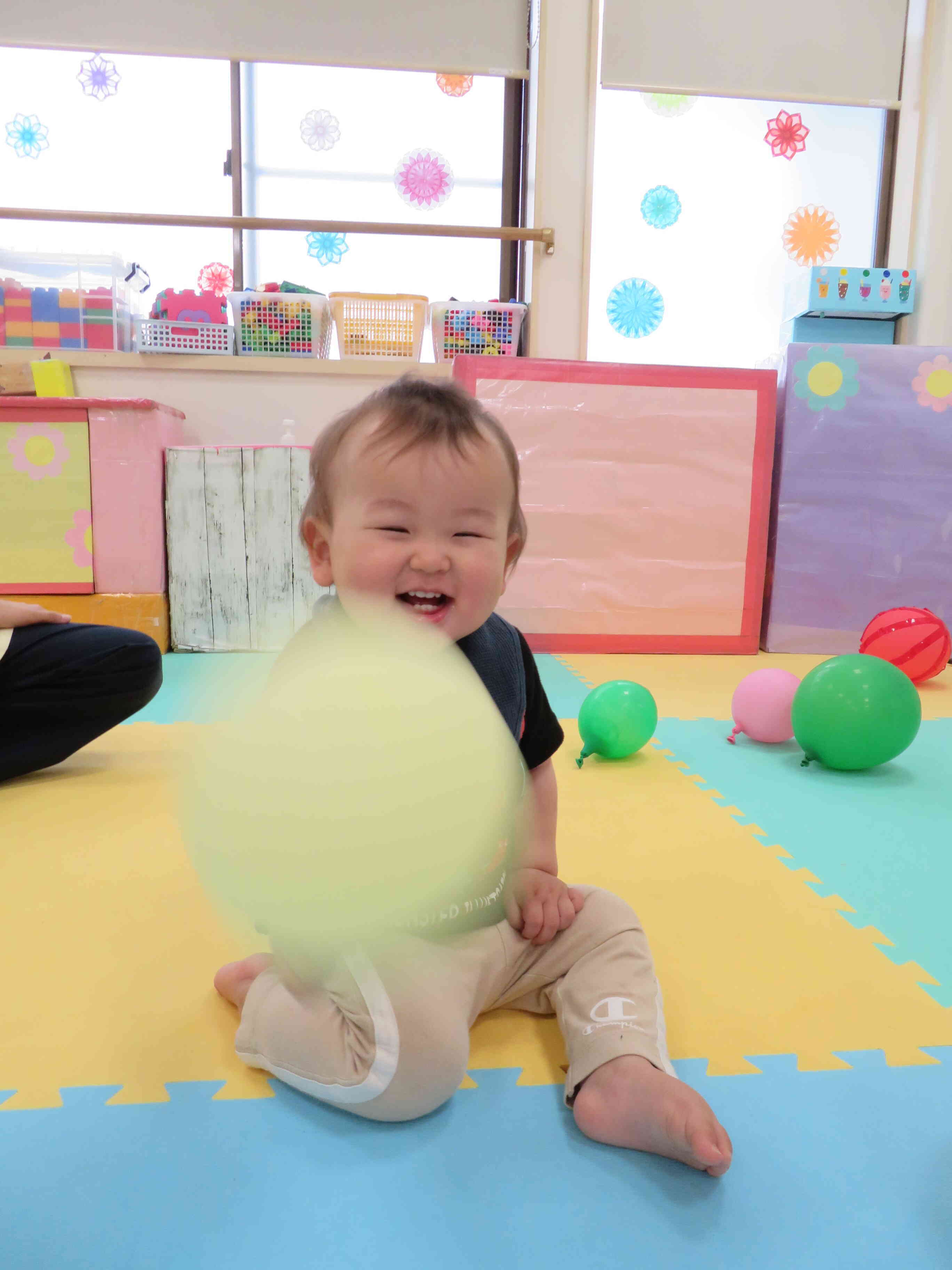 今日は広いお部屋にお邪魔して思いっきり風船あそびを楽しむ0歳児さん。先生のまねっこをして風船を振ると、トントン床にあたって面白い音がするのが面白い！！