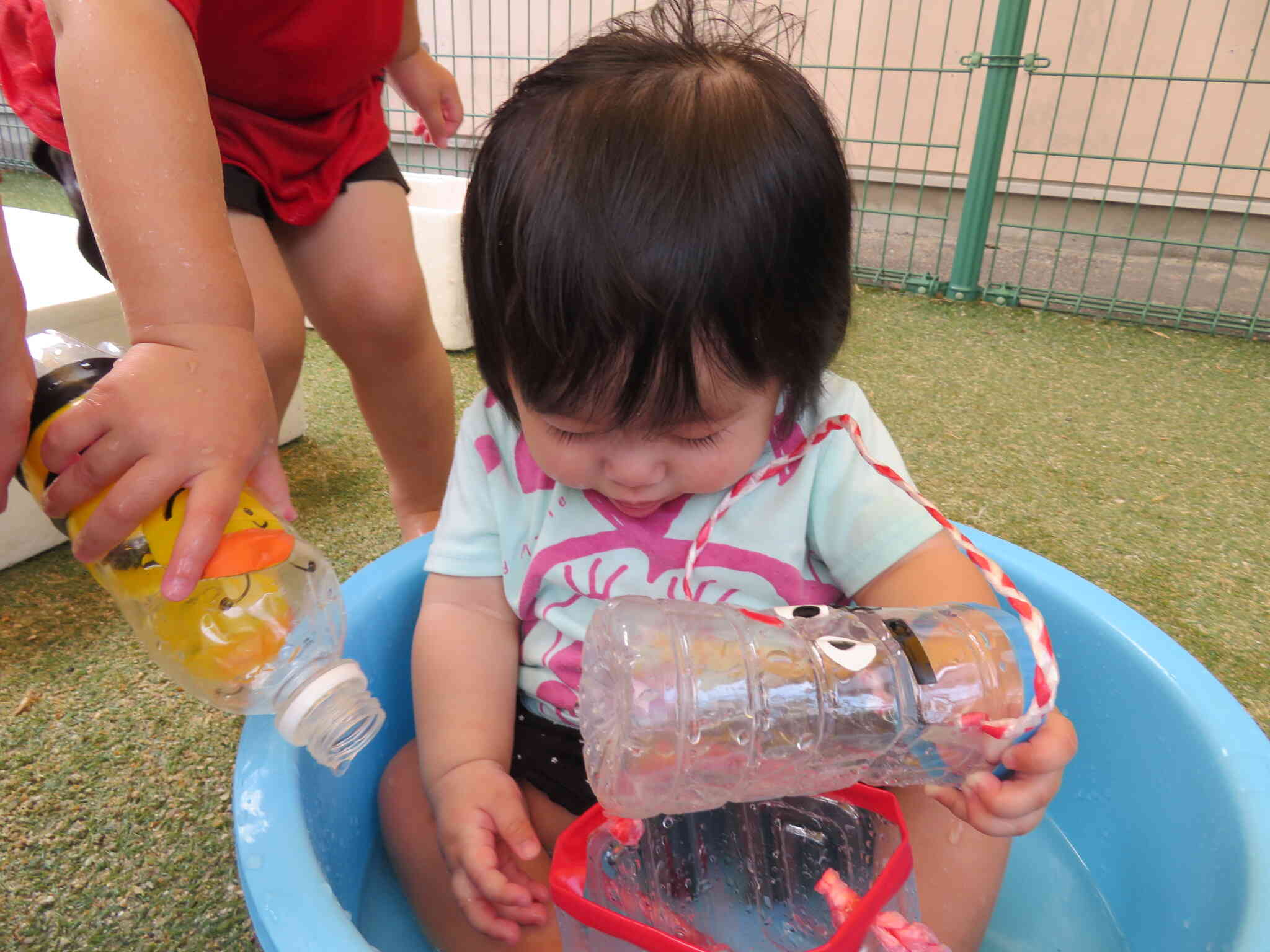 小さなお友だちも水あそびを楽しんでいます。おねえちゃんがどうぞってお水を入れてくれたよ。
