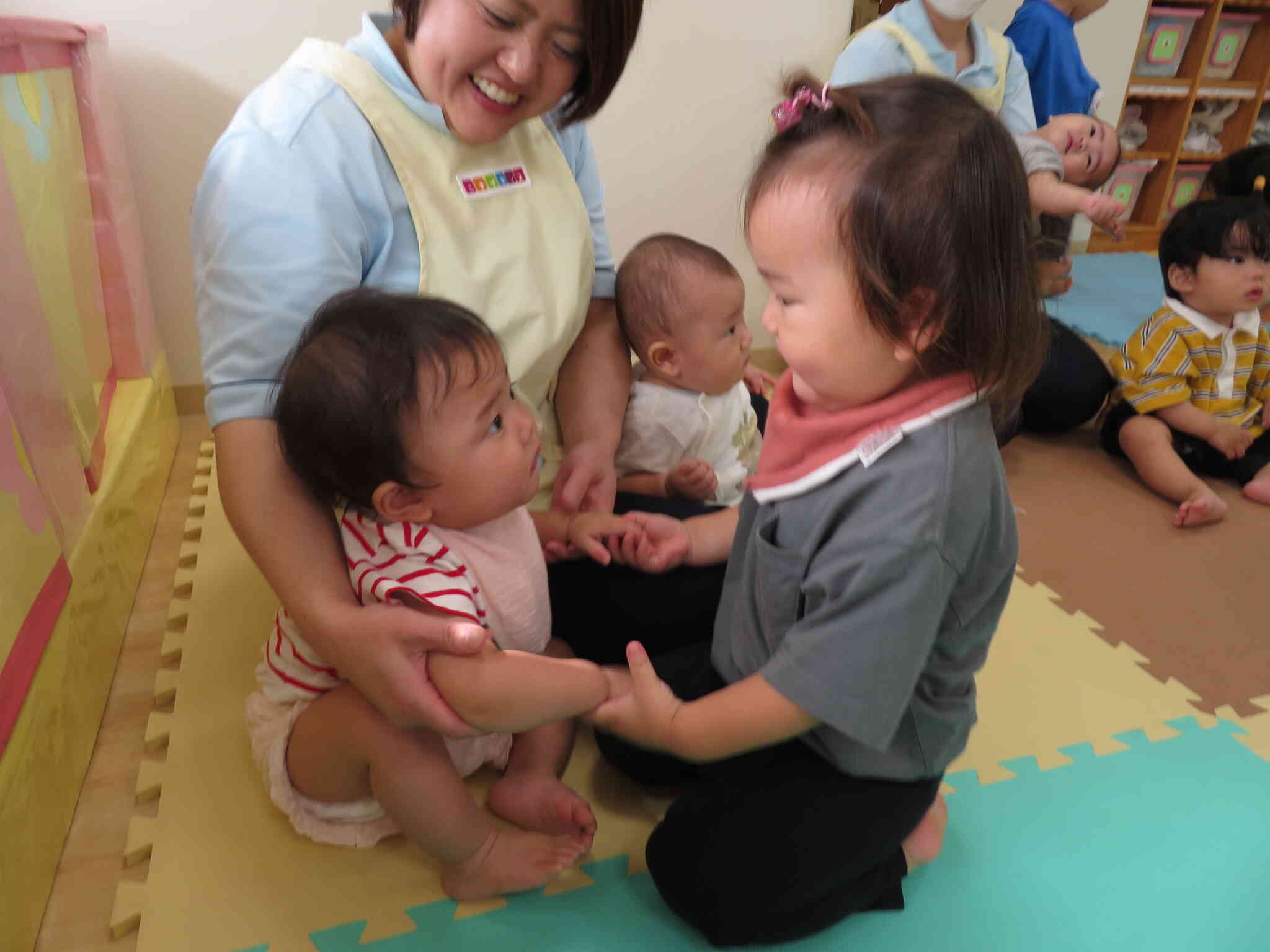 小さなお友だちにやさしい1歳児さん。一緒に手をつなごうって0歳児さんを誘います。