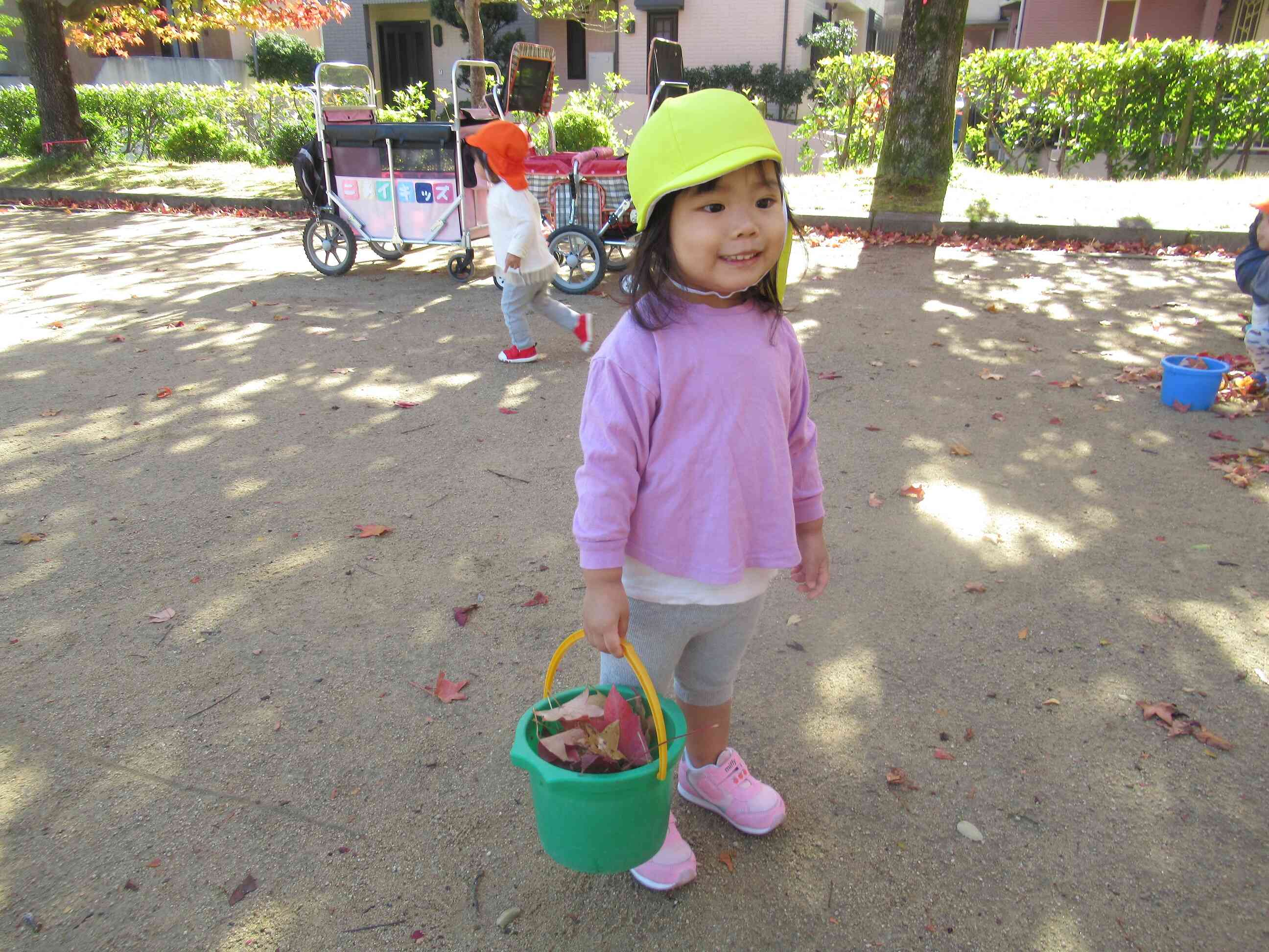 バケツにたくさん落ち葉を入れていますね。お買い物をしているみたいでとてもかわいいです。