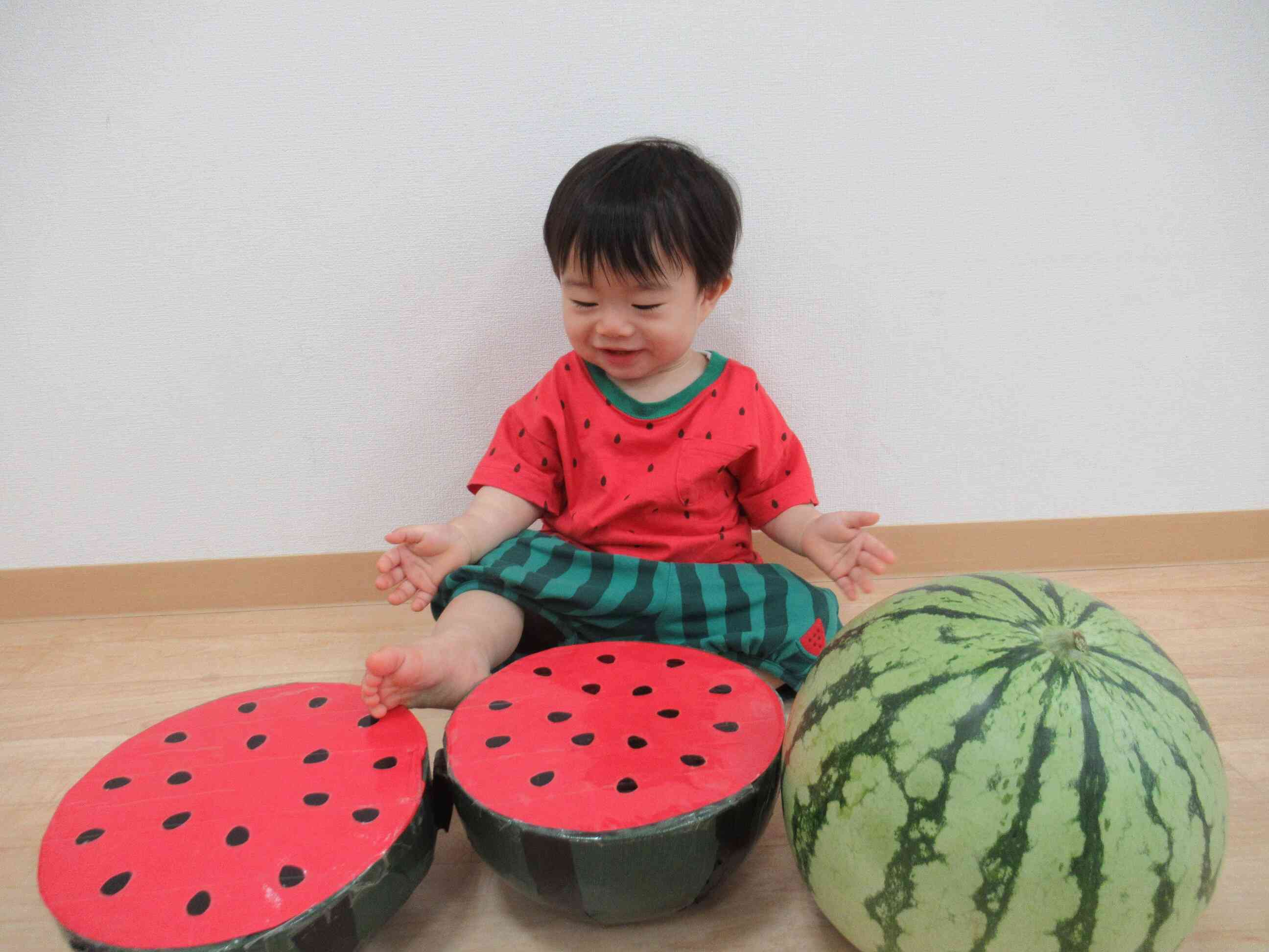 ８月に入園してくれました０歳児クラスのお友達です。園の裏庭で採れた大きなスイカと一緒に写真を撮りました。服もスイカなのでスイカが一杯です。
