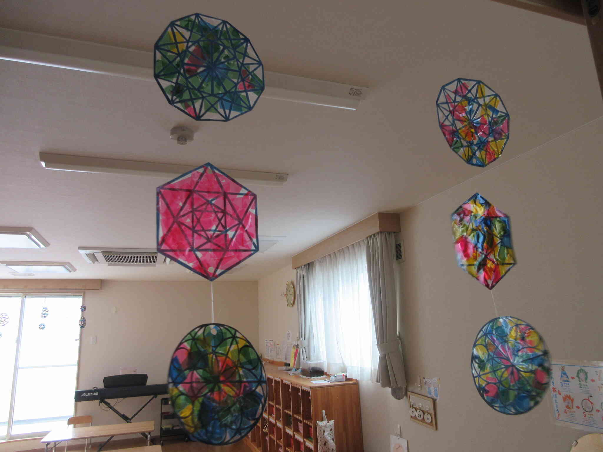 子どもたちが配色を考えて作ったサンキャッチャー。光を受けて輝きながら揺れています。