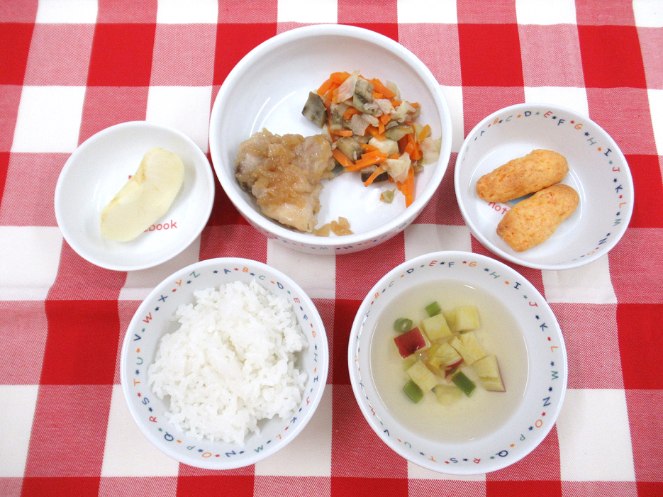 ～今日の献立～ご飯、焼き油淋鶏、茄子のツナ味噌炒め、サツマイモのスープ、りんご　　にんじんスティックパン（おやつ）