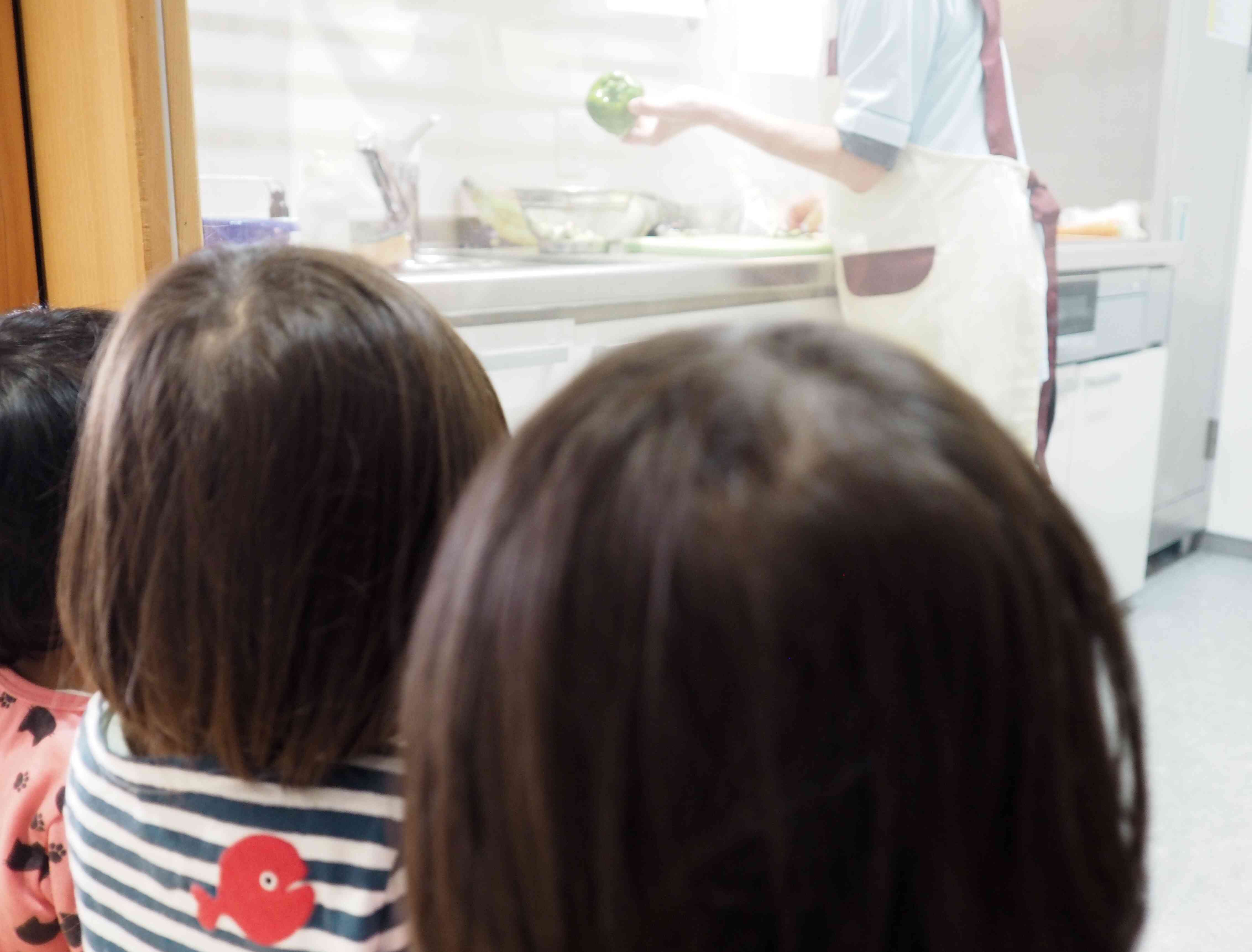 栄養士が調理している様子を、真剣に見ています。