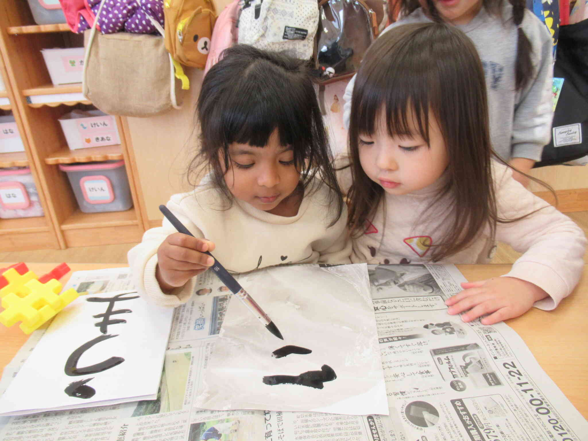 お友達に見守られ　筆しっかりもってますね　すごい