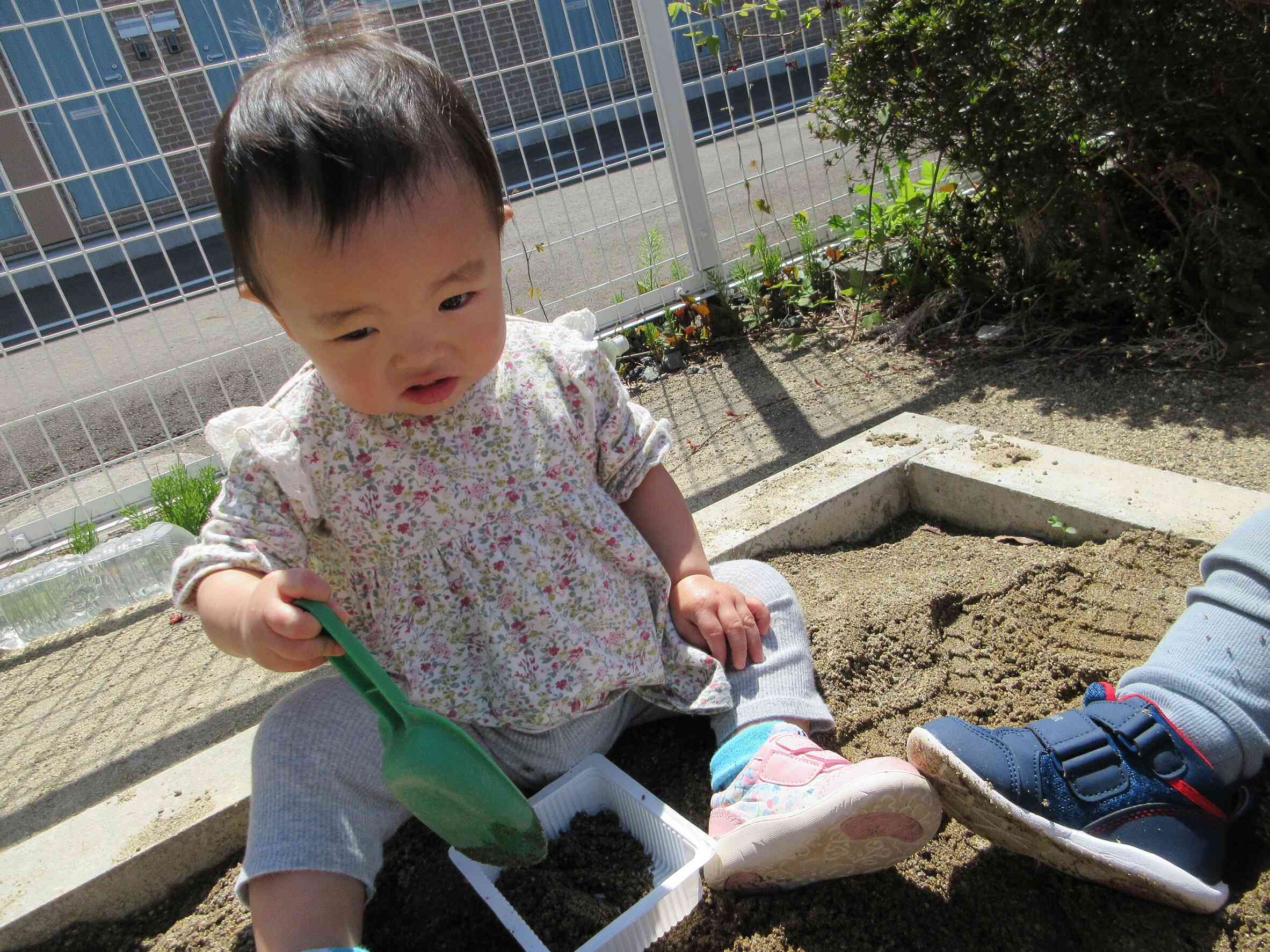 スコップを使って容器の中に砂を入れてるよ。