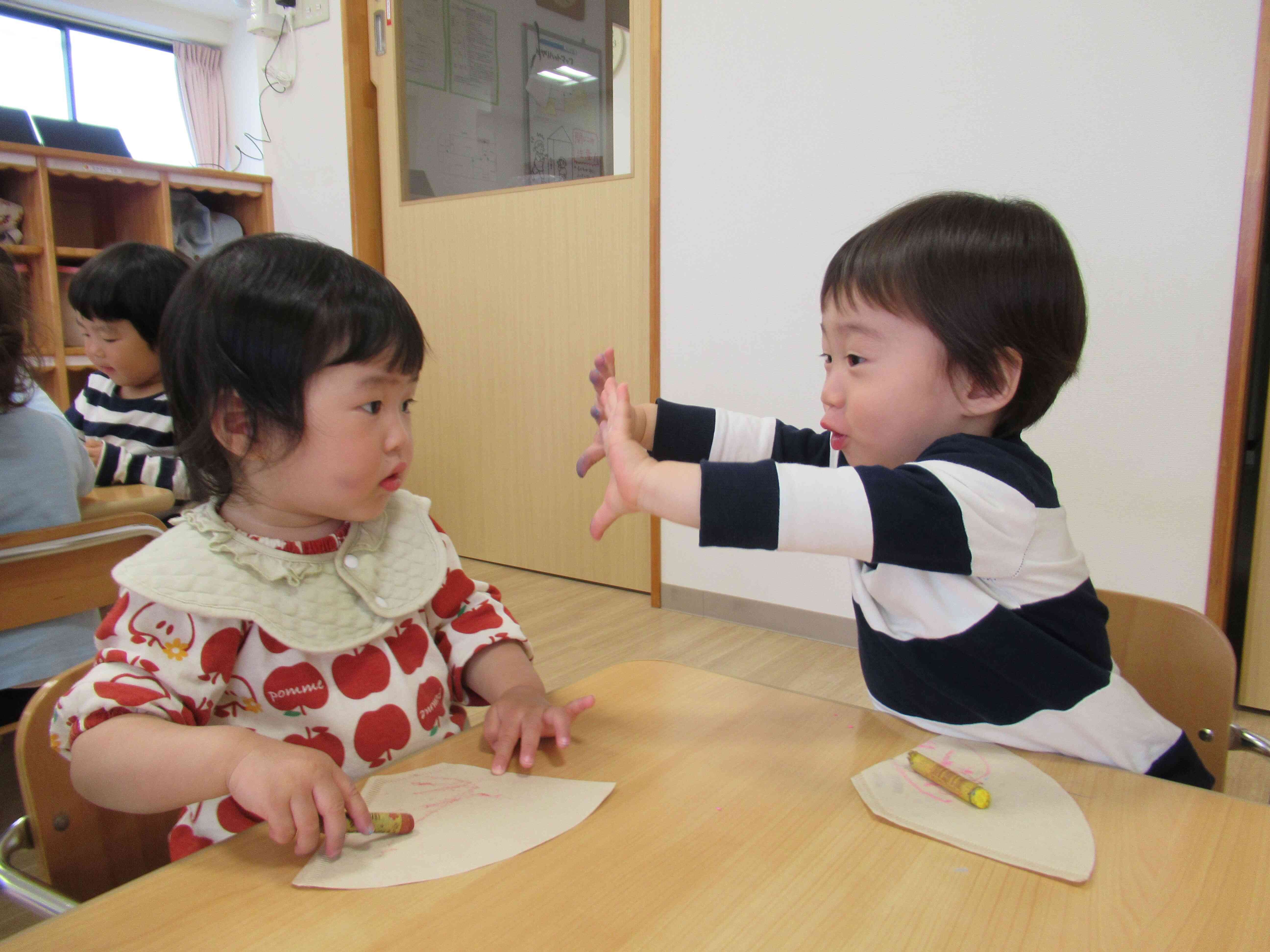 手にクレヨンがついたよ。自分の手を見てビックリ‼　お友達にも見せる姿がかわいいですね。