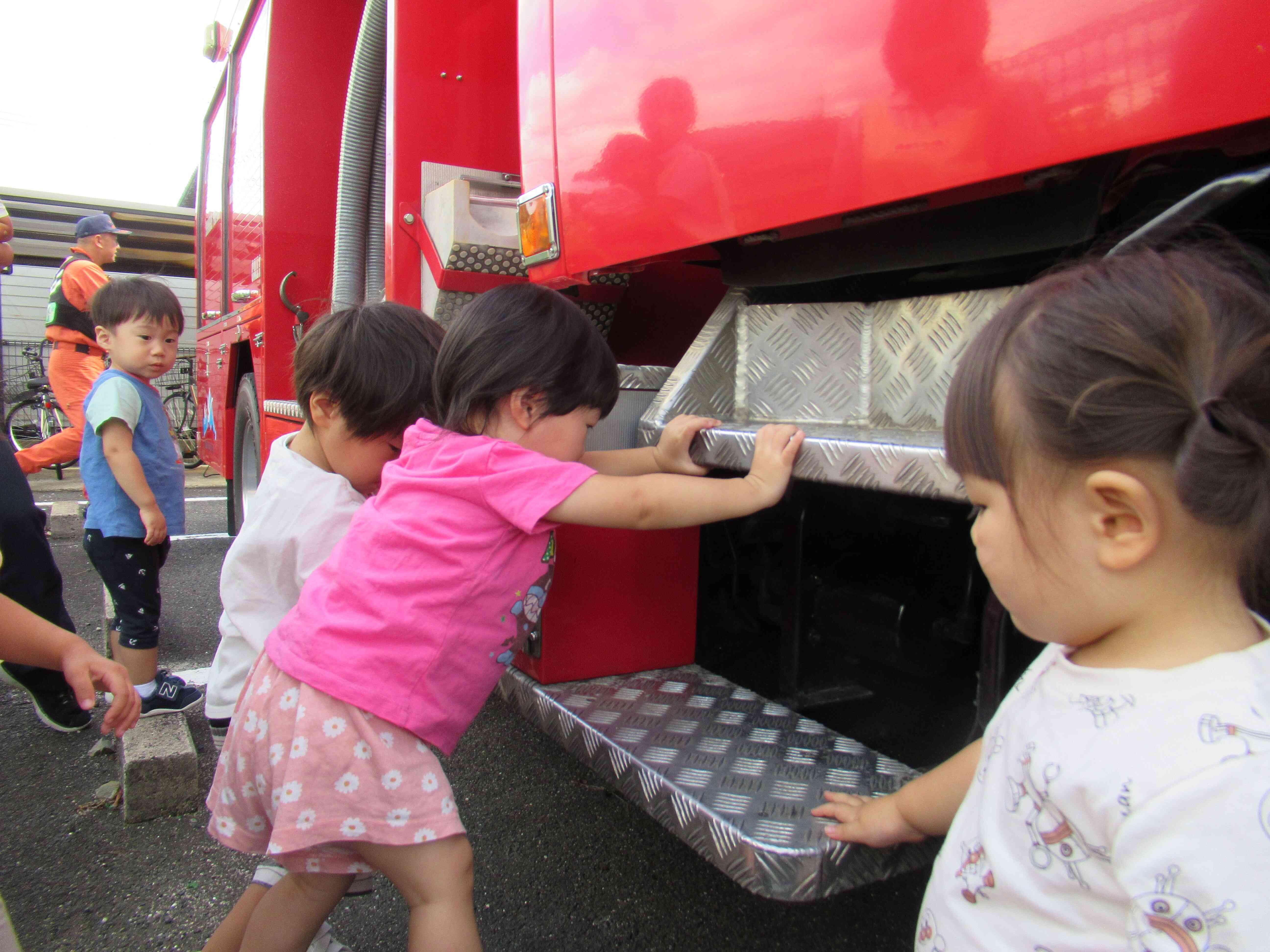横から見ると消防車に乗る為のステップがありました。足が届くかな？片足をあげ、登ることに挑戦中です。