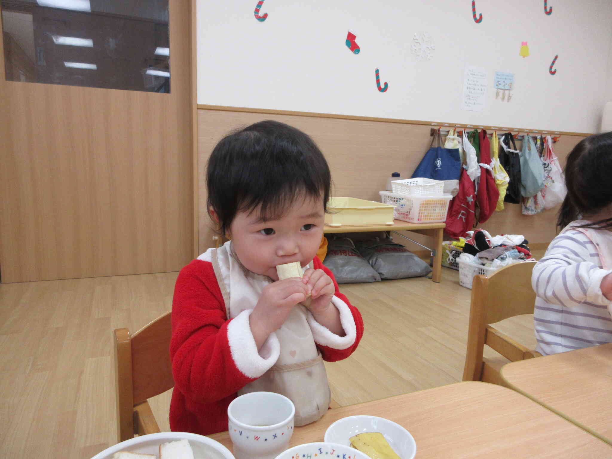 サンタクロースの衣装を着て給食です！（1歳児）