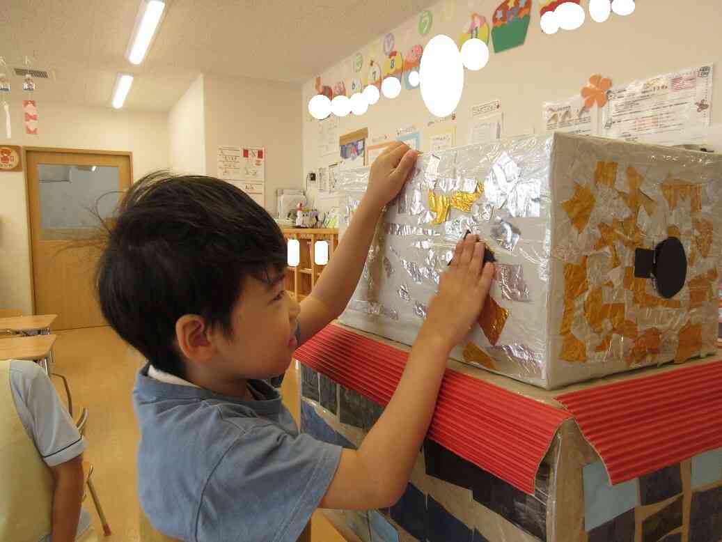 りす・ぱんだ組（3.4歳児）にちぎってもらった金色の折り紙は側面（2階部分の予定）に♡仕上げにきりん組（5歳児）が窓をつけました。