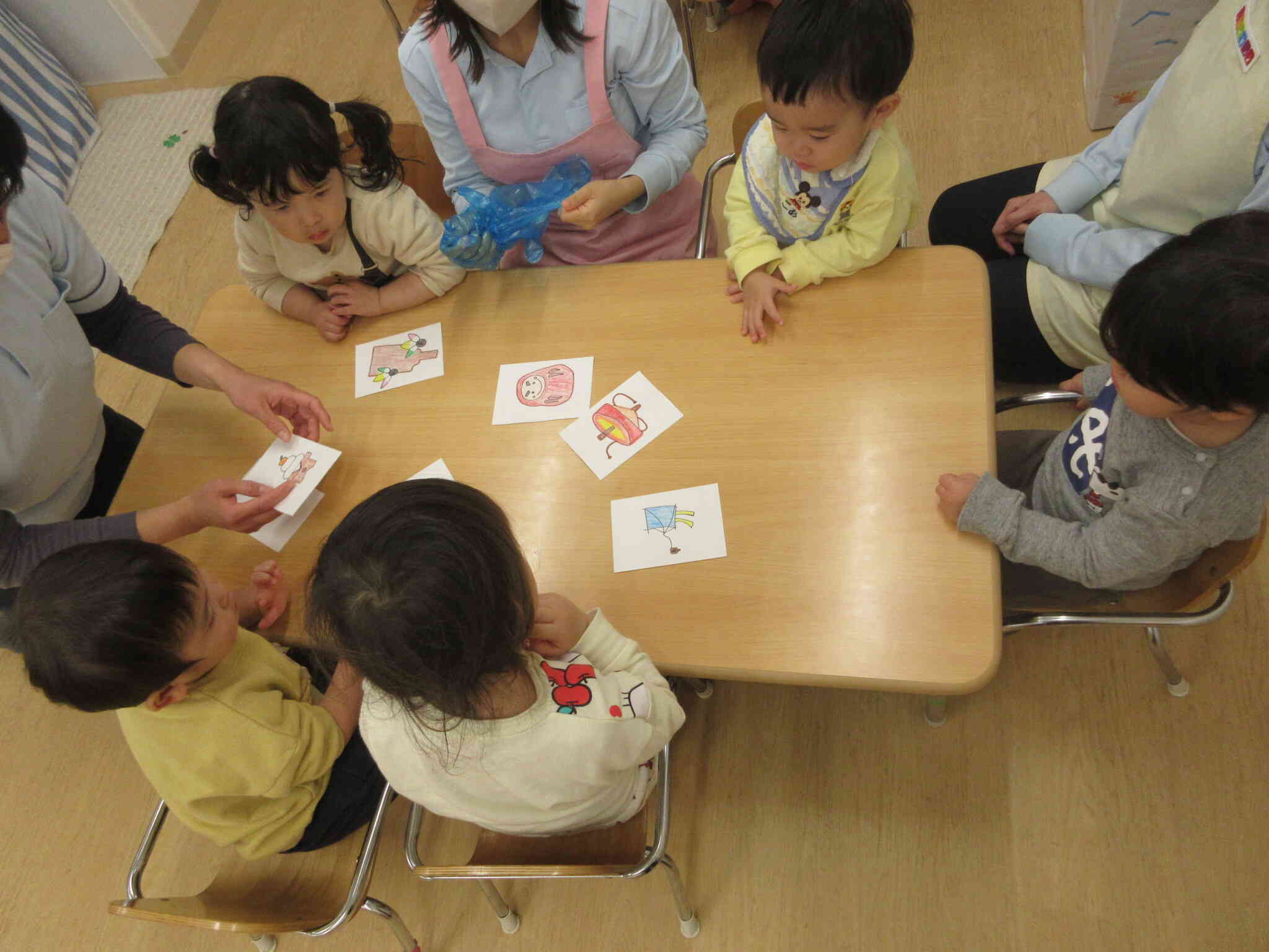 「くるくる回して遊ぶおもちゃは、どれかな？」子どもたちは集中してかるたを見ています。