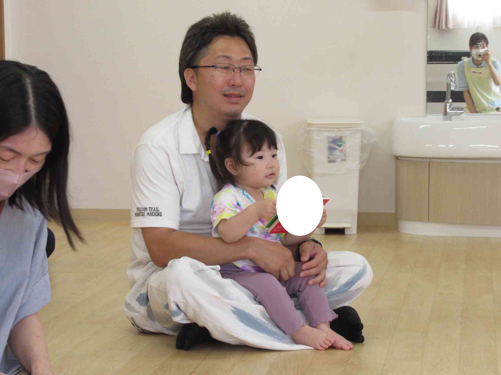 お父さんのお膝に座ってお話聞いてるよ。