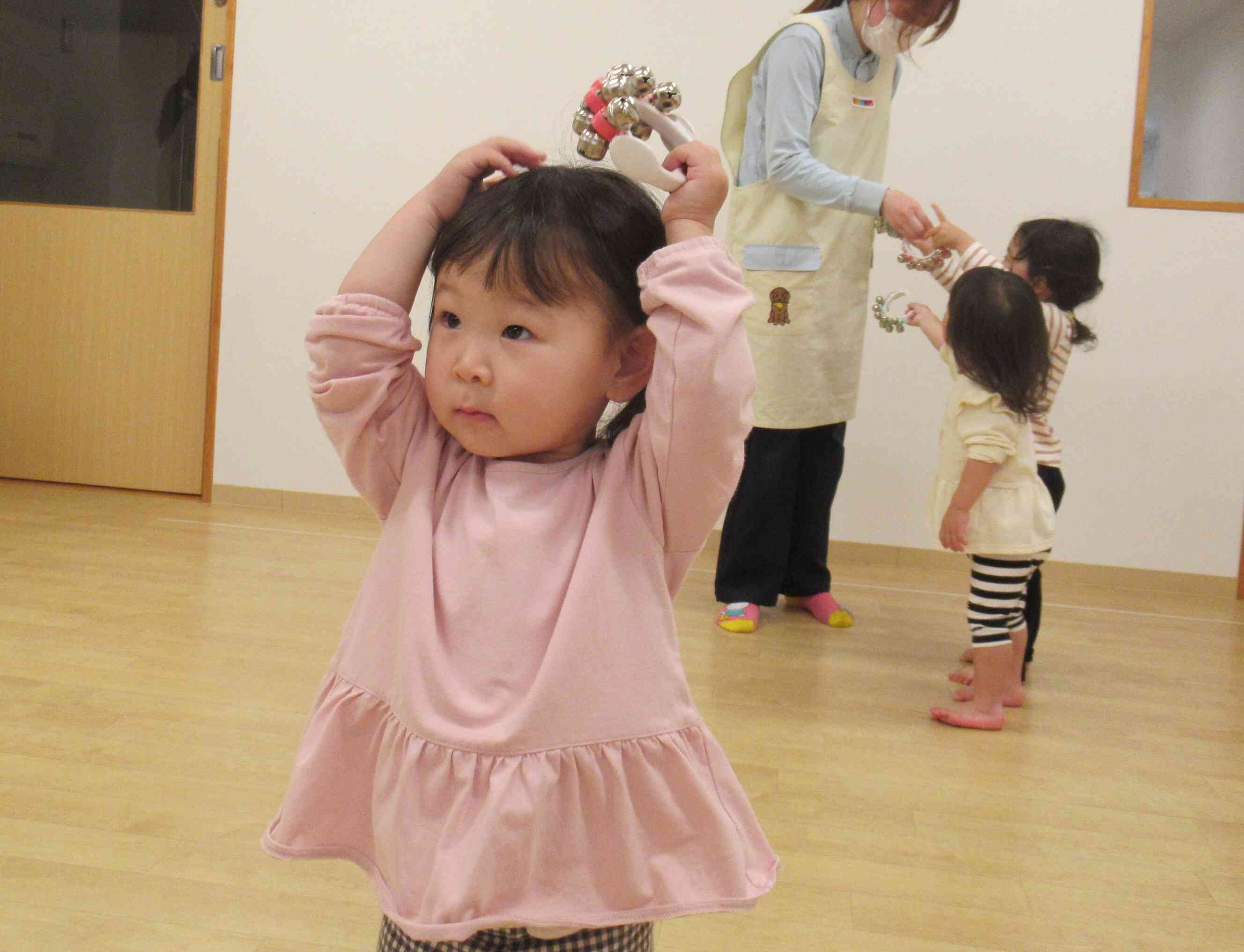 鈴を持って、初めての曲に合わせて鳴らしながら体の部位を触っていきます。「あたま～」とそ～っと頭で鈴を鳴らす２歳児Yちゃんです