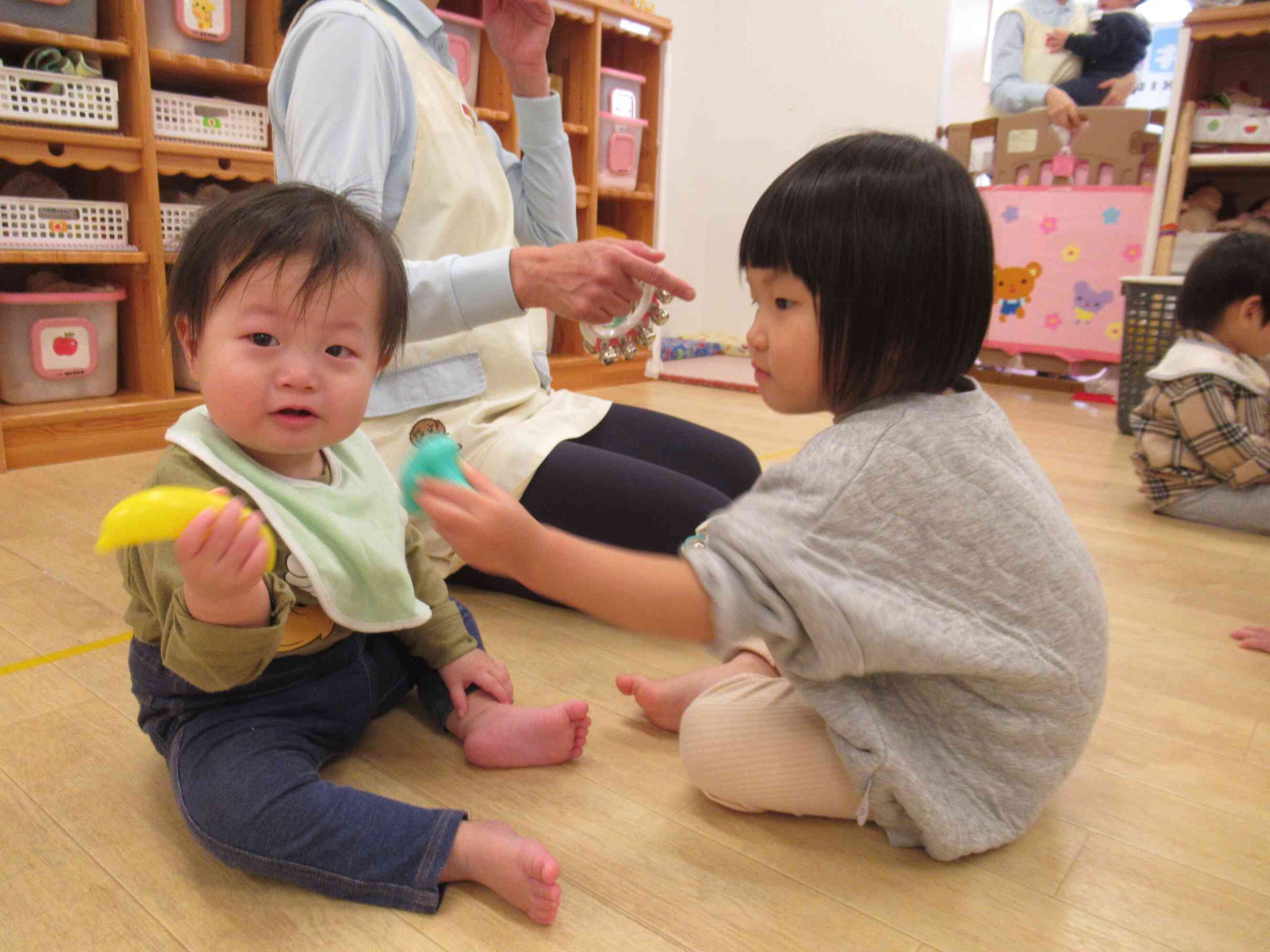 0歳児のお友だちに楽器を「どうぞ」してあげる2歳児さん、優しいね。
