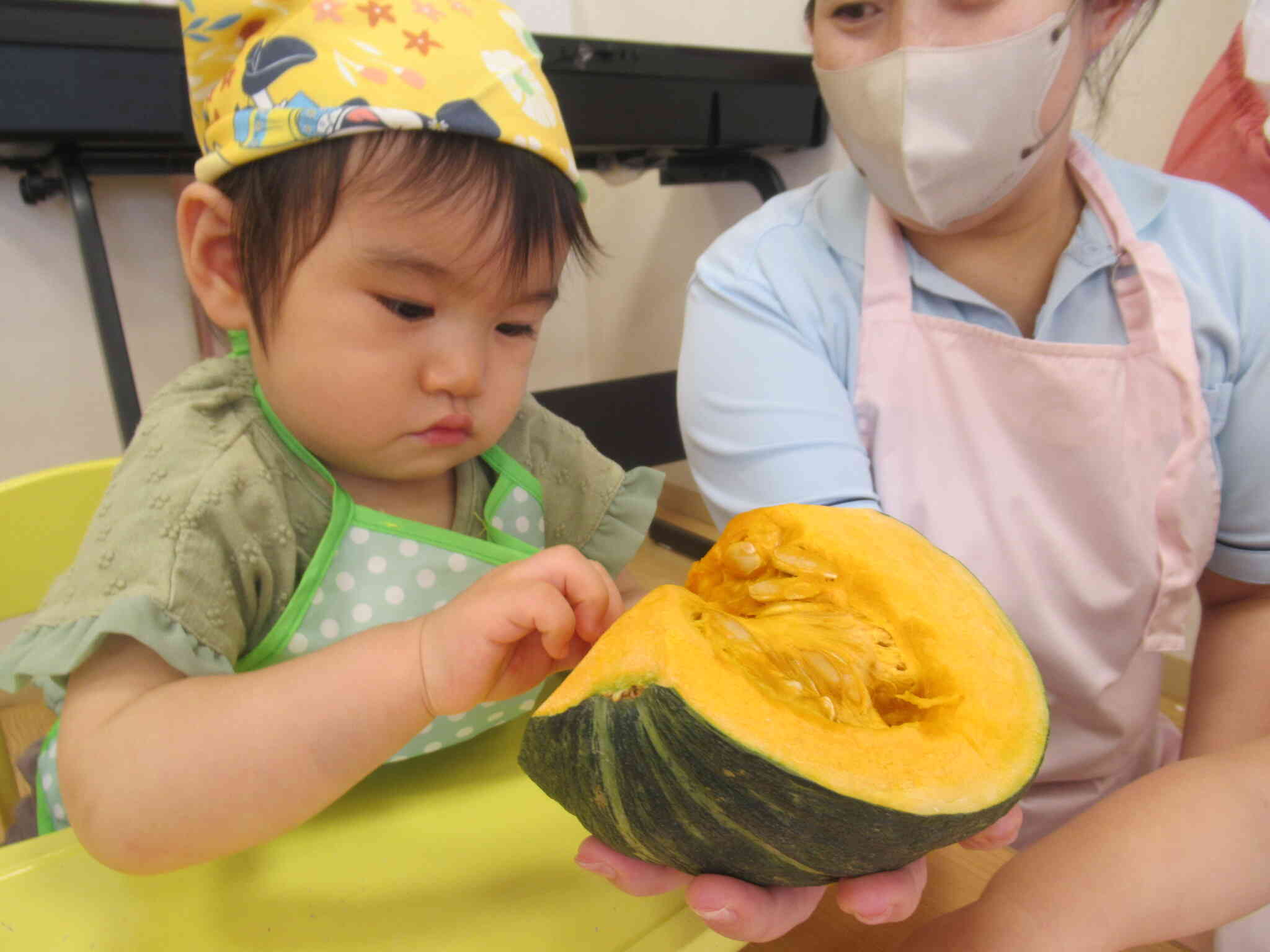 野菜当てクイズの後はお野菜を触ってみました。大きなたねに興味津々の０歳児Ｓさんです。