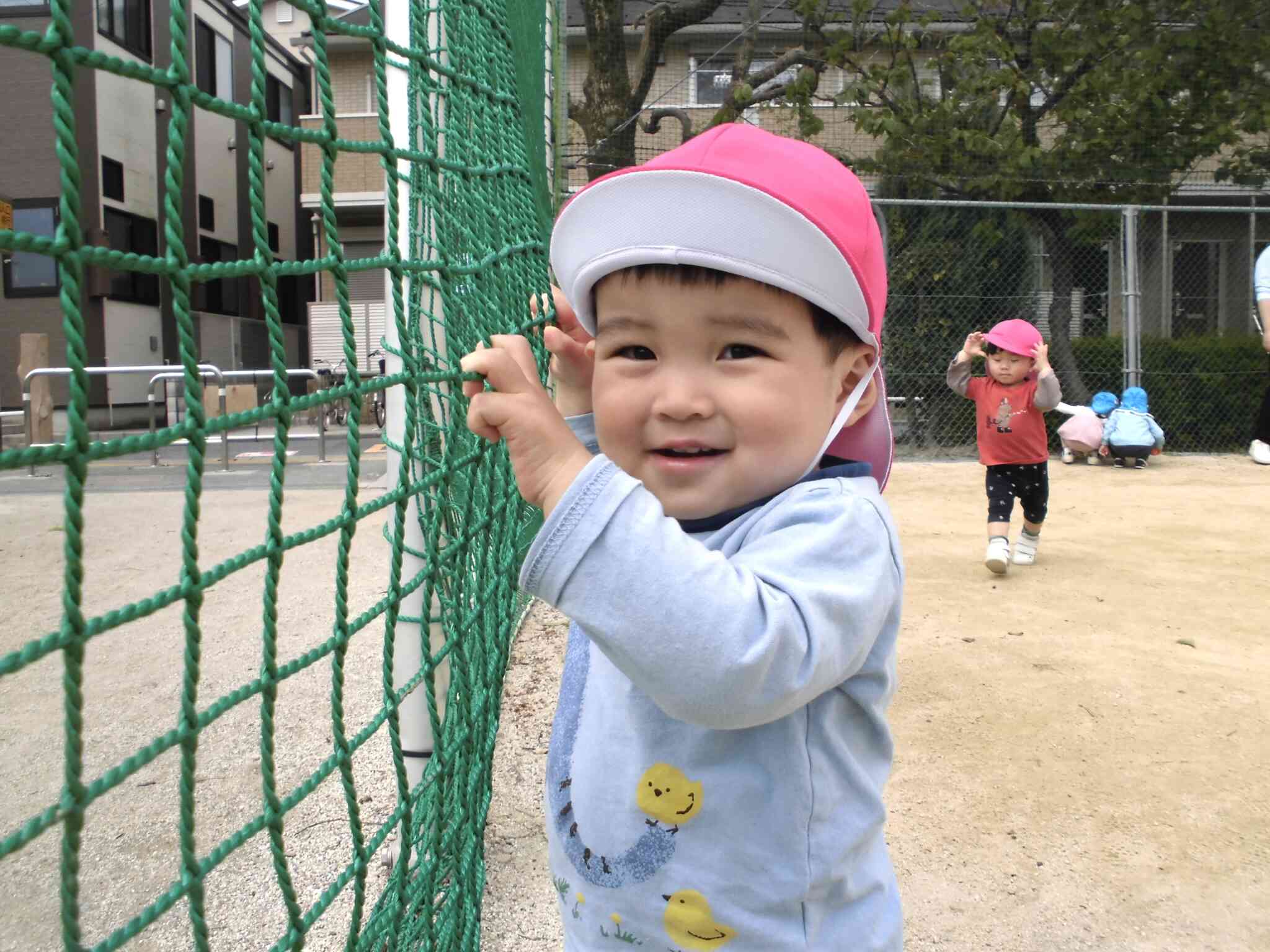 公園のしきりにあるネットが気に入り、捕まりながら歩いて探索中！