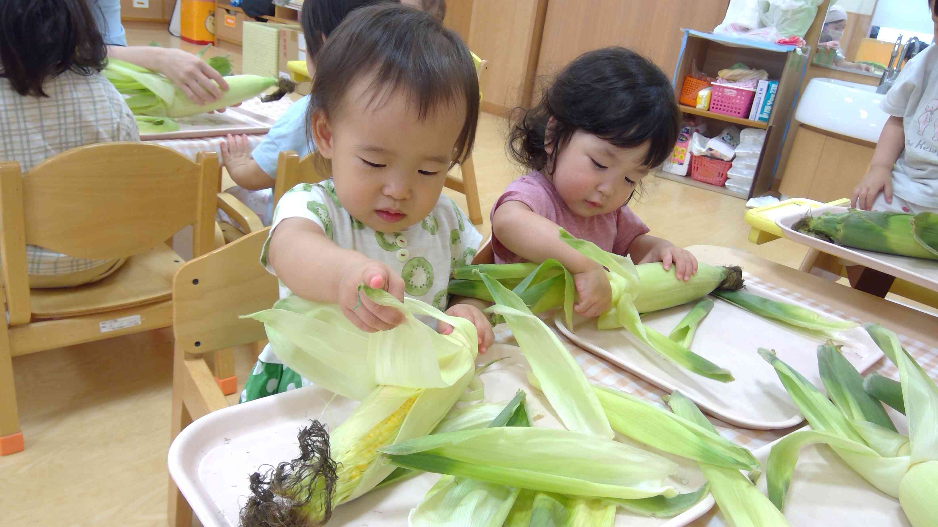 とうもろこしの皮をむいたよ！～1歳児あひる組～