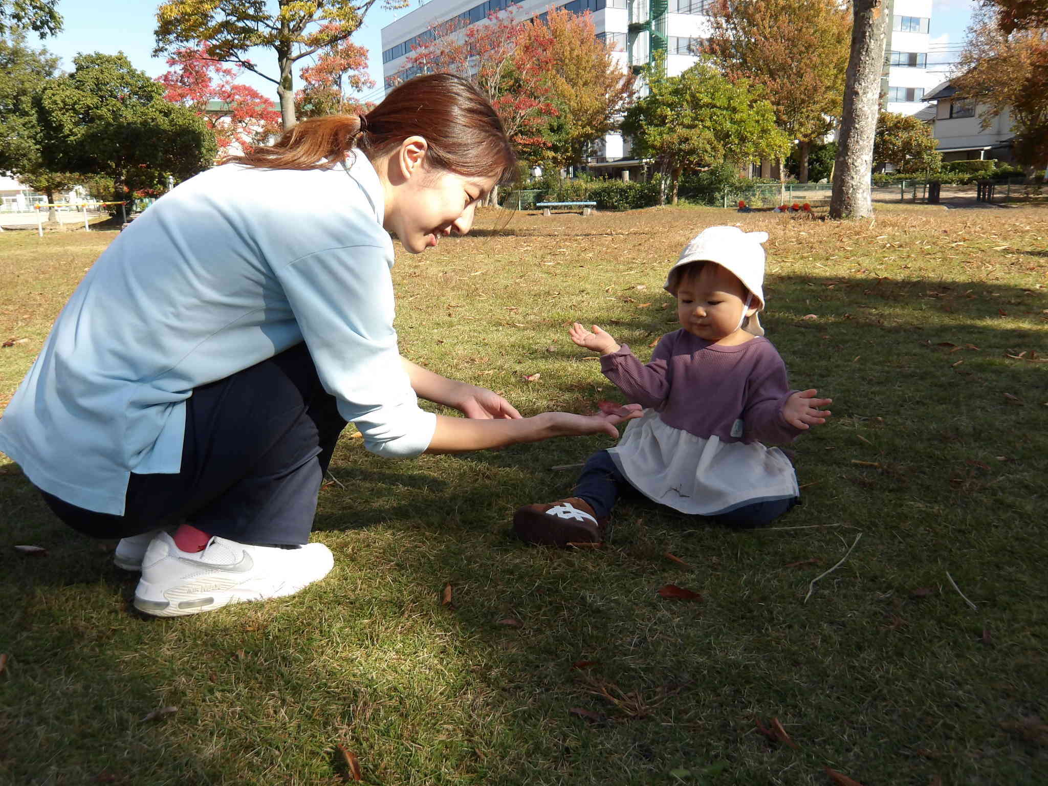 保育者が落ち葉を見つけ、一緒に見て観察していました。