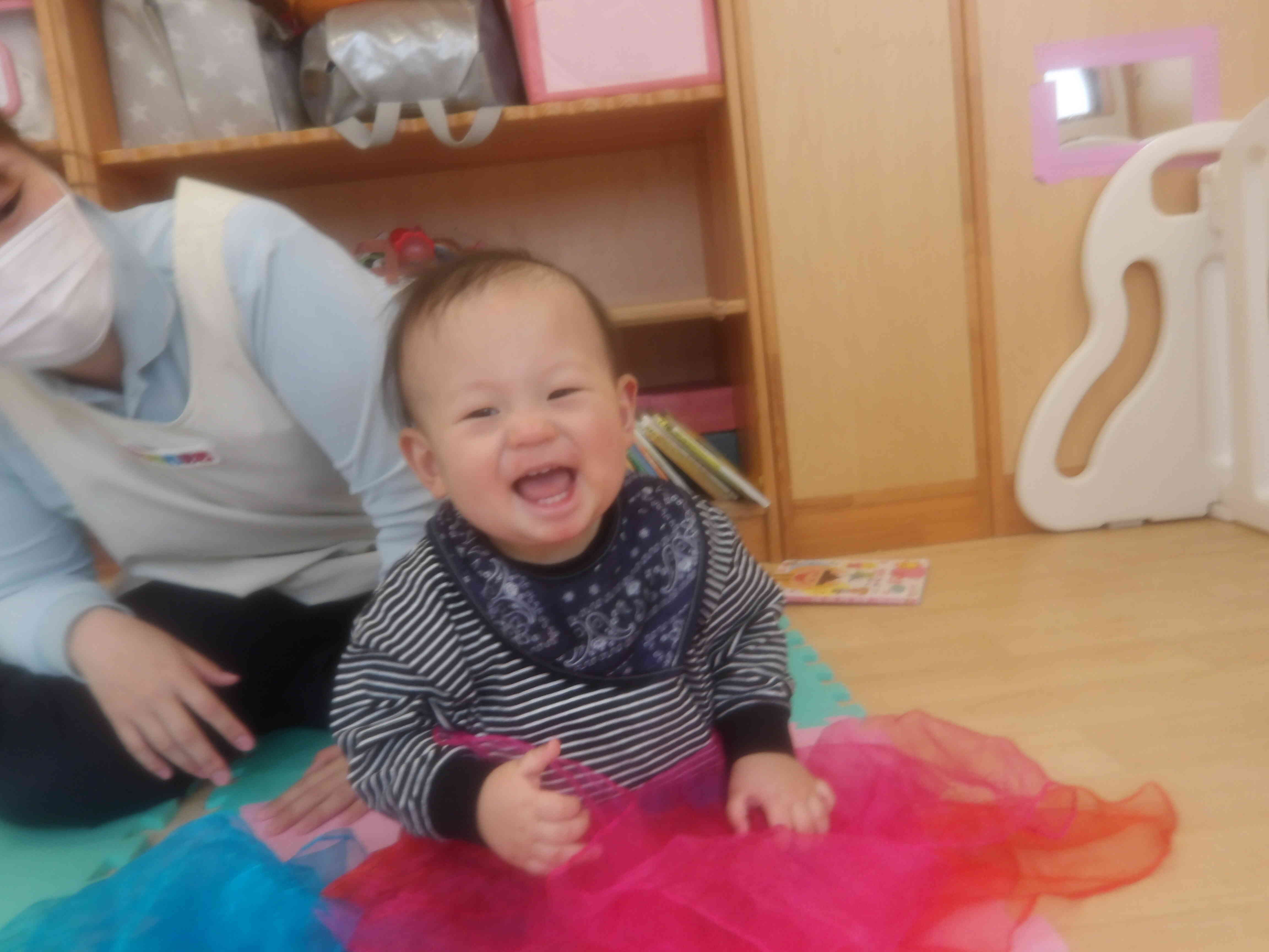 オーガンジーでふれあい遊び楽しいね。保育者が「ばぁ！」とするとにっこり笑顔のNちゃん。