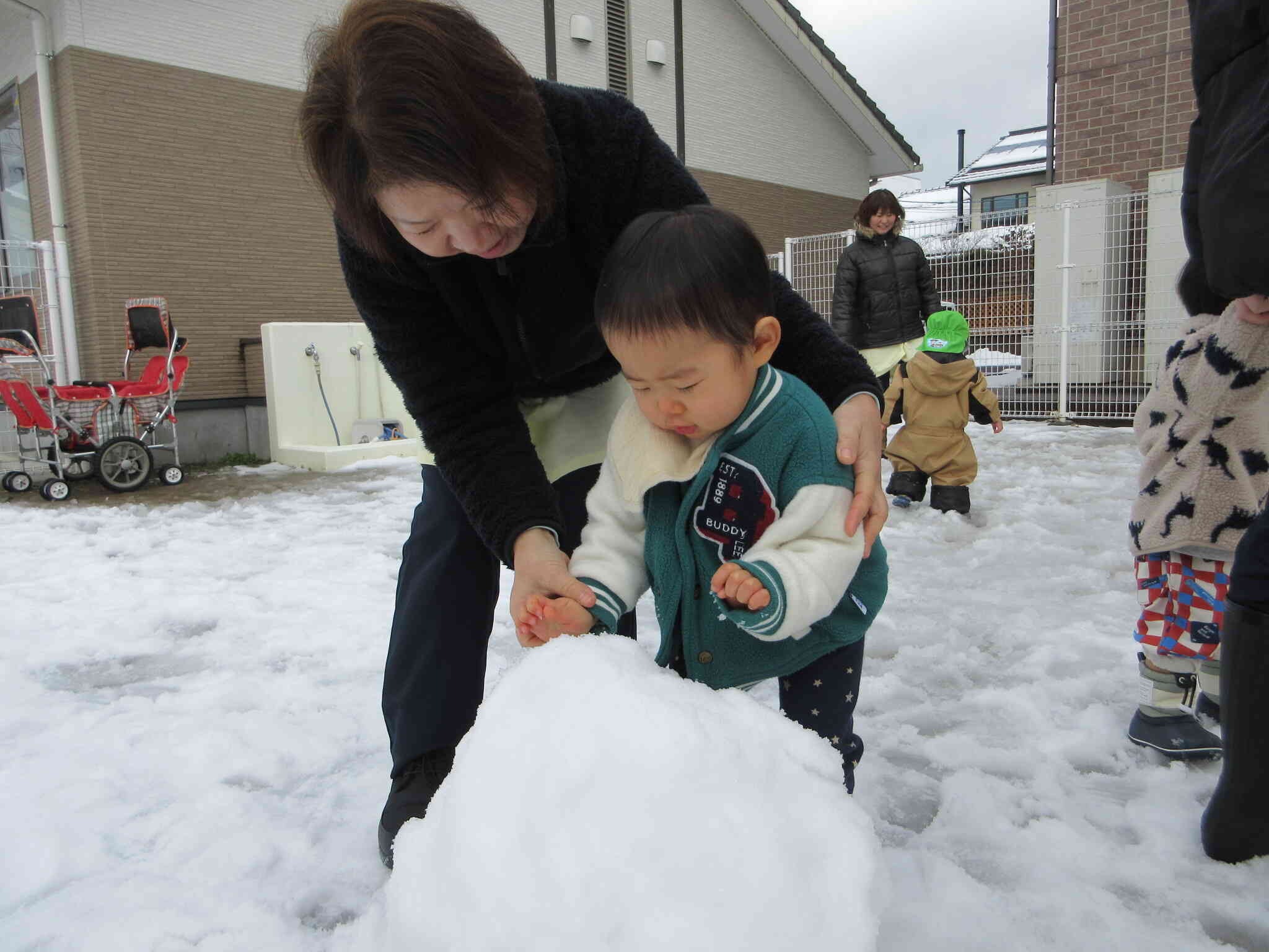 おおきな雪のかたまりにおそるおそる手を触れてみようとするKくん「ひゃっ、冷たい」