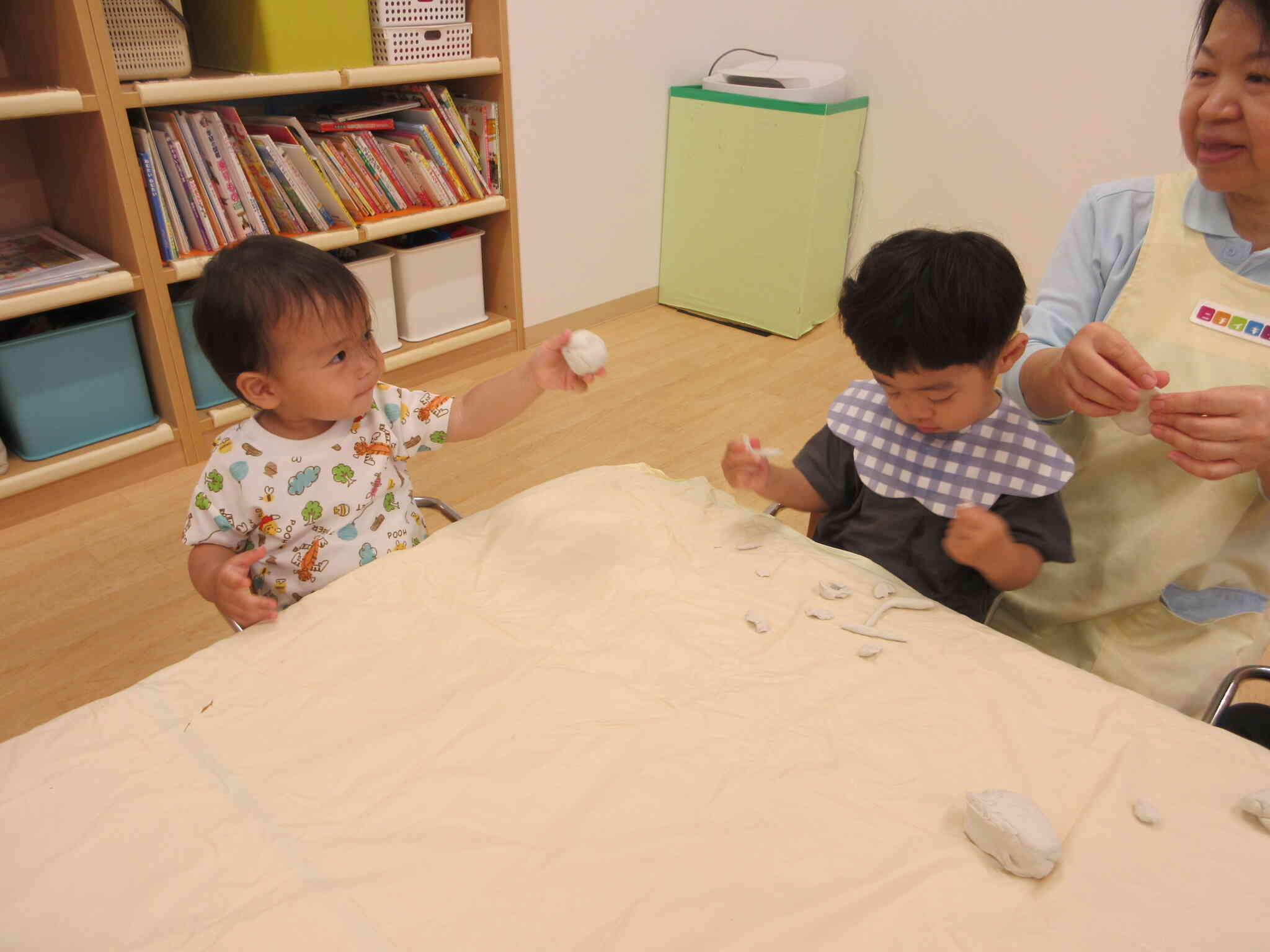 まんまるのお団子ができた！と先生に見せているYくんと先生が伸ばした粘土を小さく小さくちぎっていくTくん